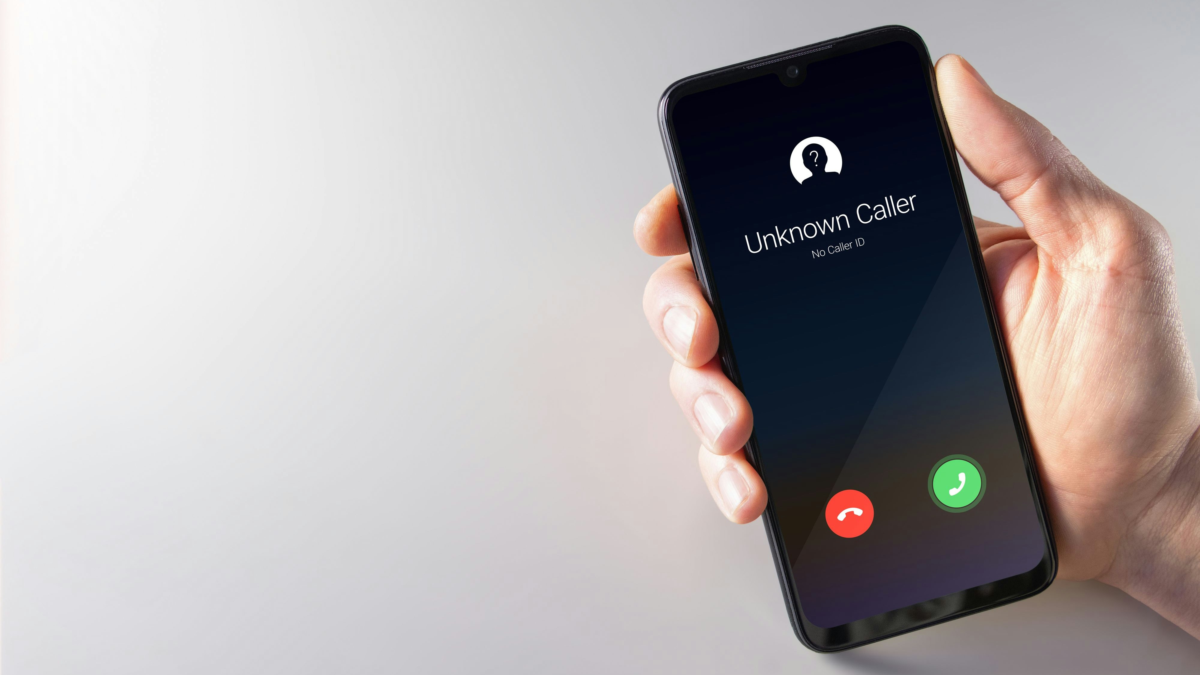 Male hand holding a smartphone with unknown caller displayed on screen. Privacy, fraud, cybercrime and spying concepts