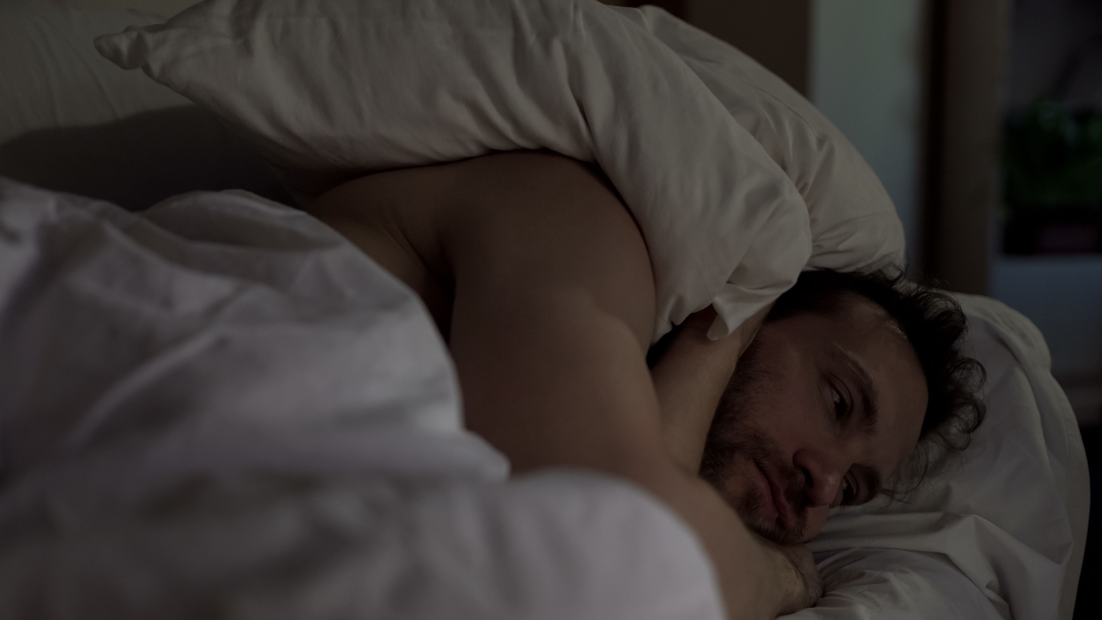 Annoyed man tossing and turning in bed unable to fall asleep, noisy neighbors