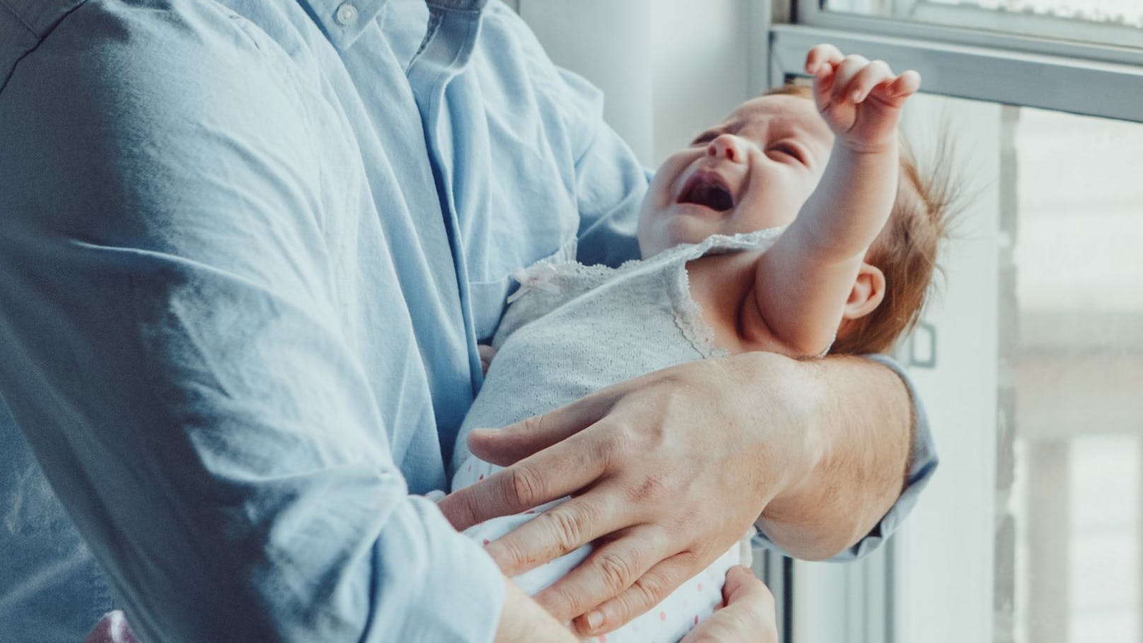 Ein Mann versucht, ein schreiendes Baby zu beruhigen. Symbolbild