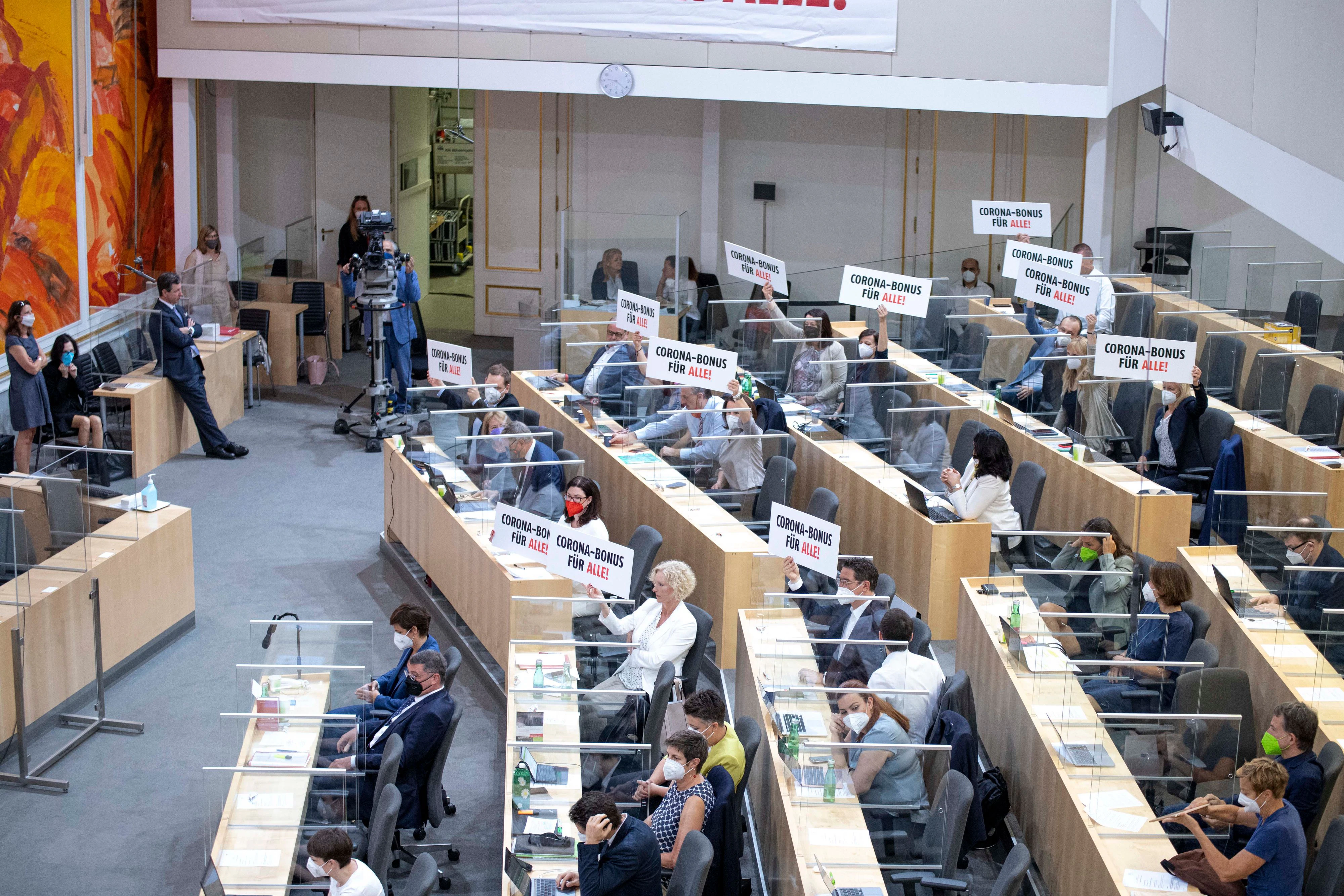 Nationalratssitzung am 16. Juni: Abgeordnete halten Schilder mit der Aufschrift "CORONA-BONUS FÜR ALLE!" in die Höhe.