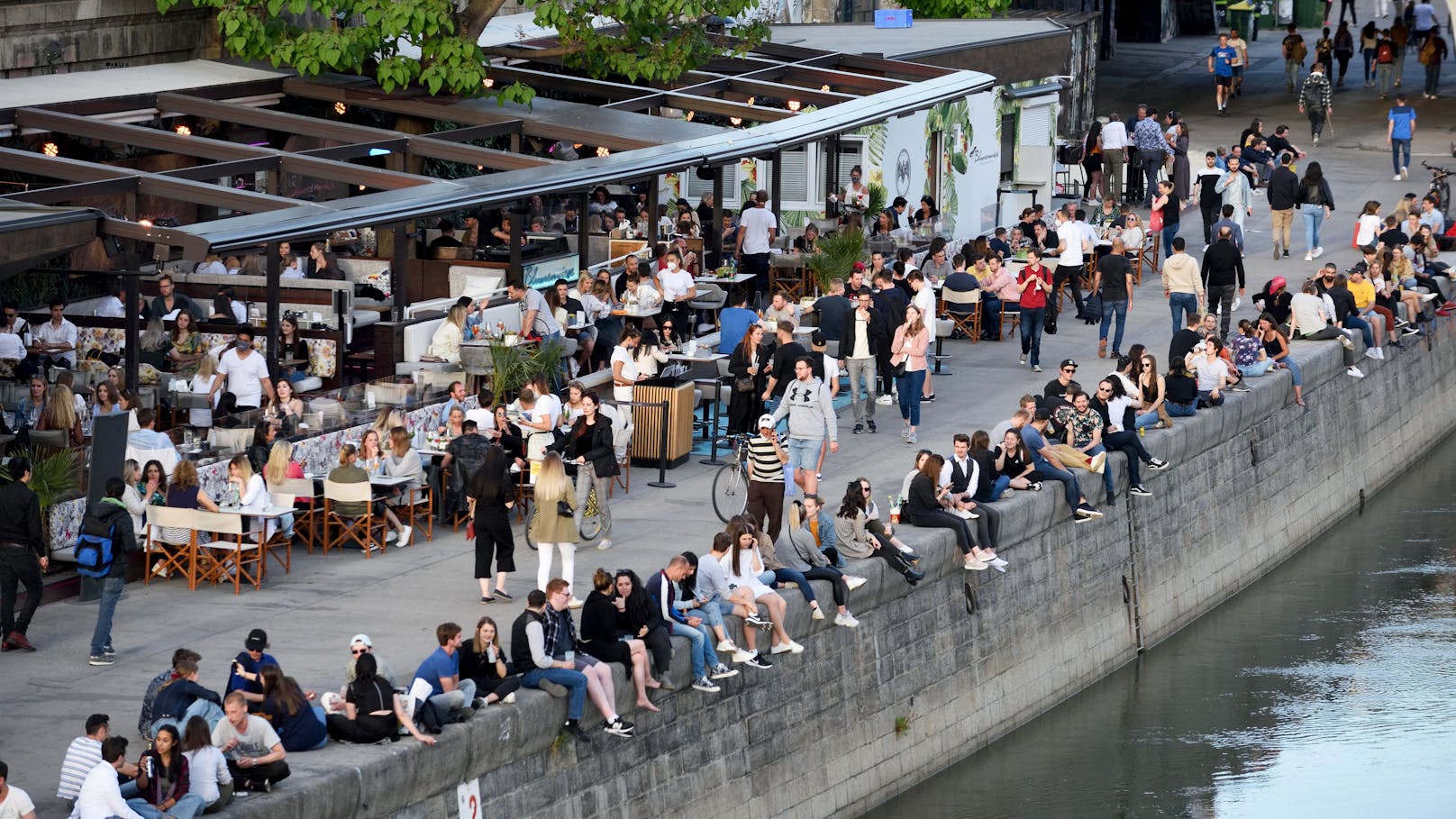 Menschen genießen den Abend am Wiener Donaukanal.