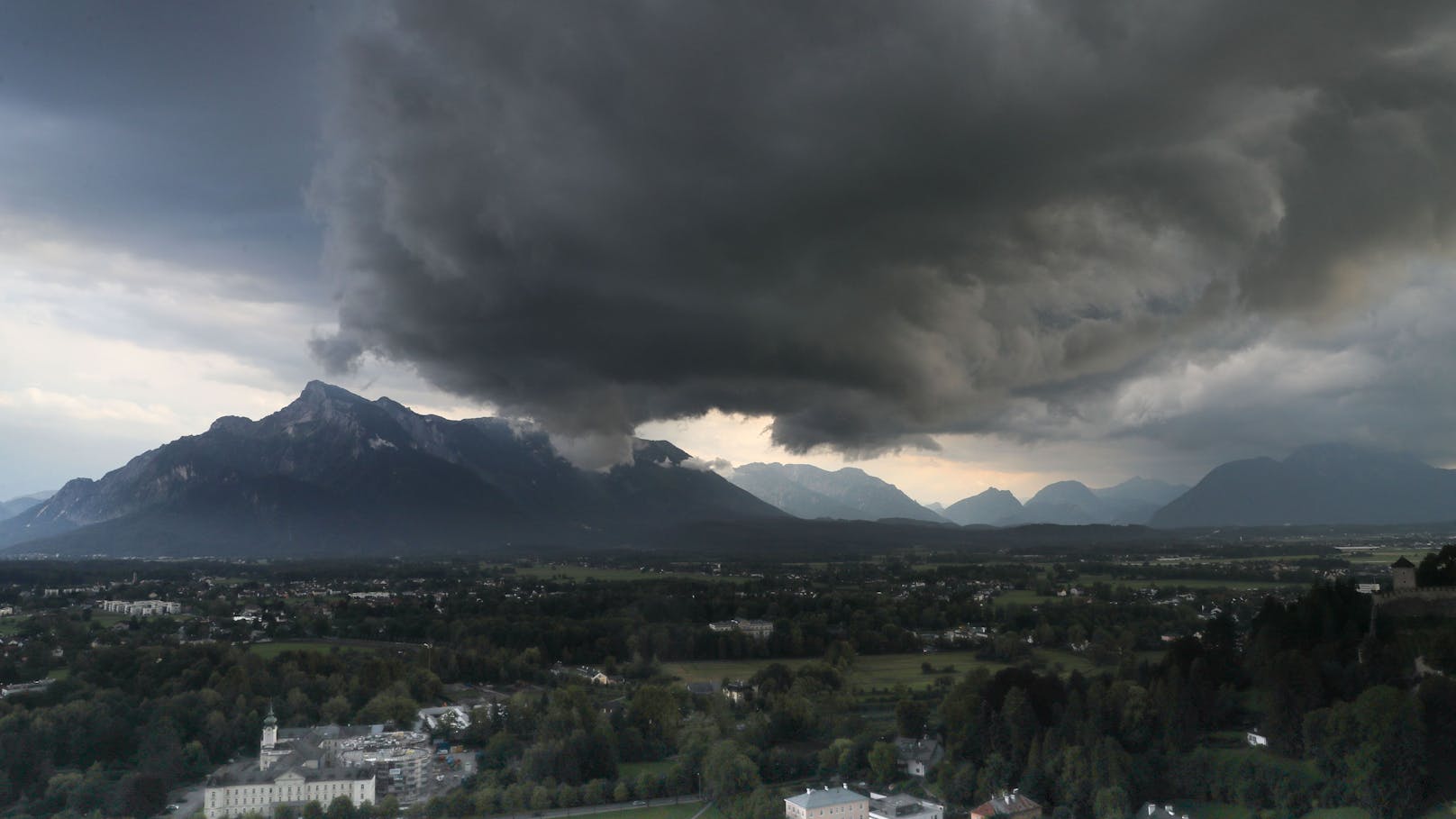 Schwarze Gewitterwolken ziehen über den Untersberg nahe der Stadt Salzburg auf.