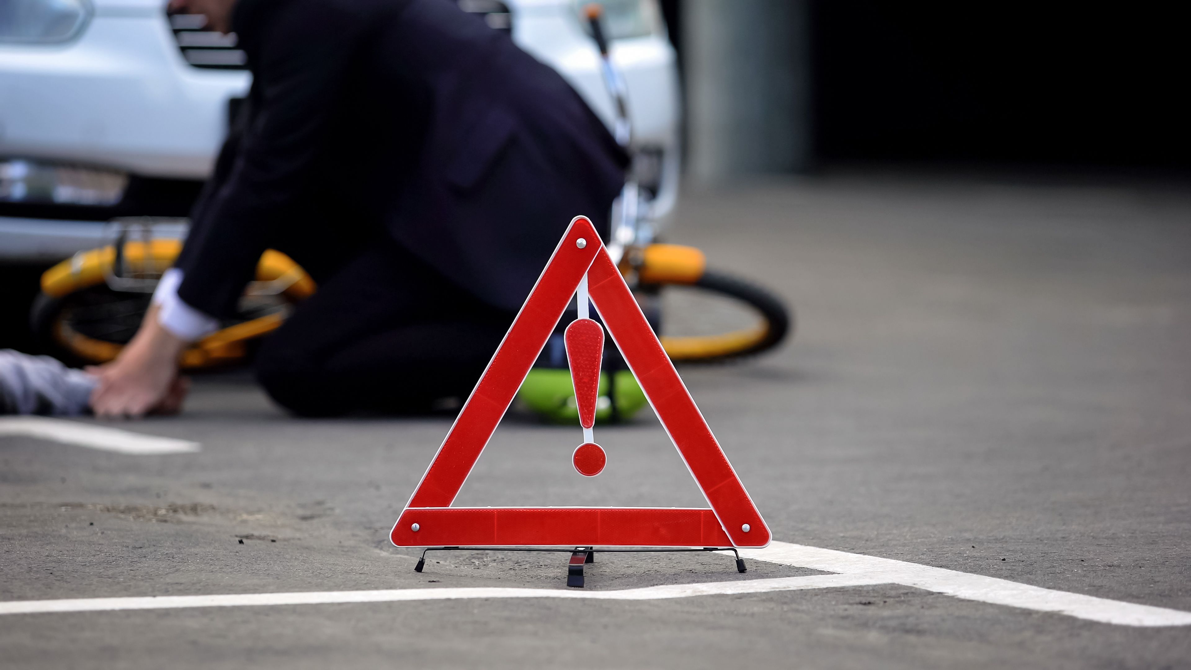Emergency red sign on road, male driver checking car crash victim pulse, death