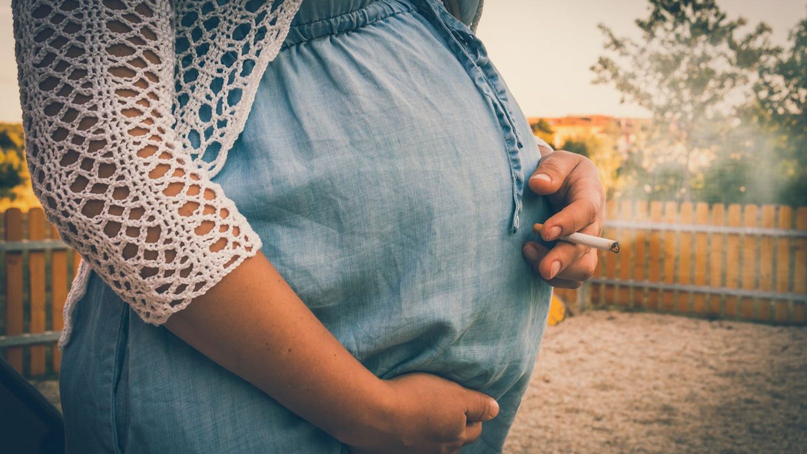 Eine schwangere Frau mit einer Zigarette in der Hand.