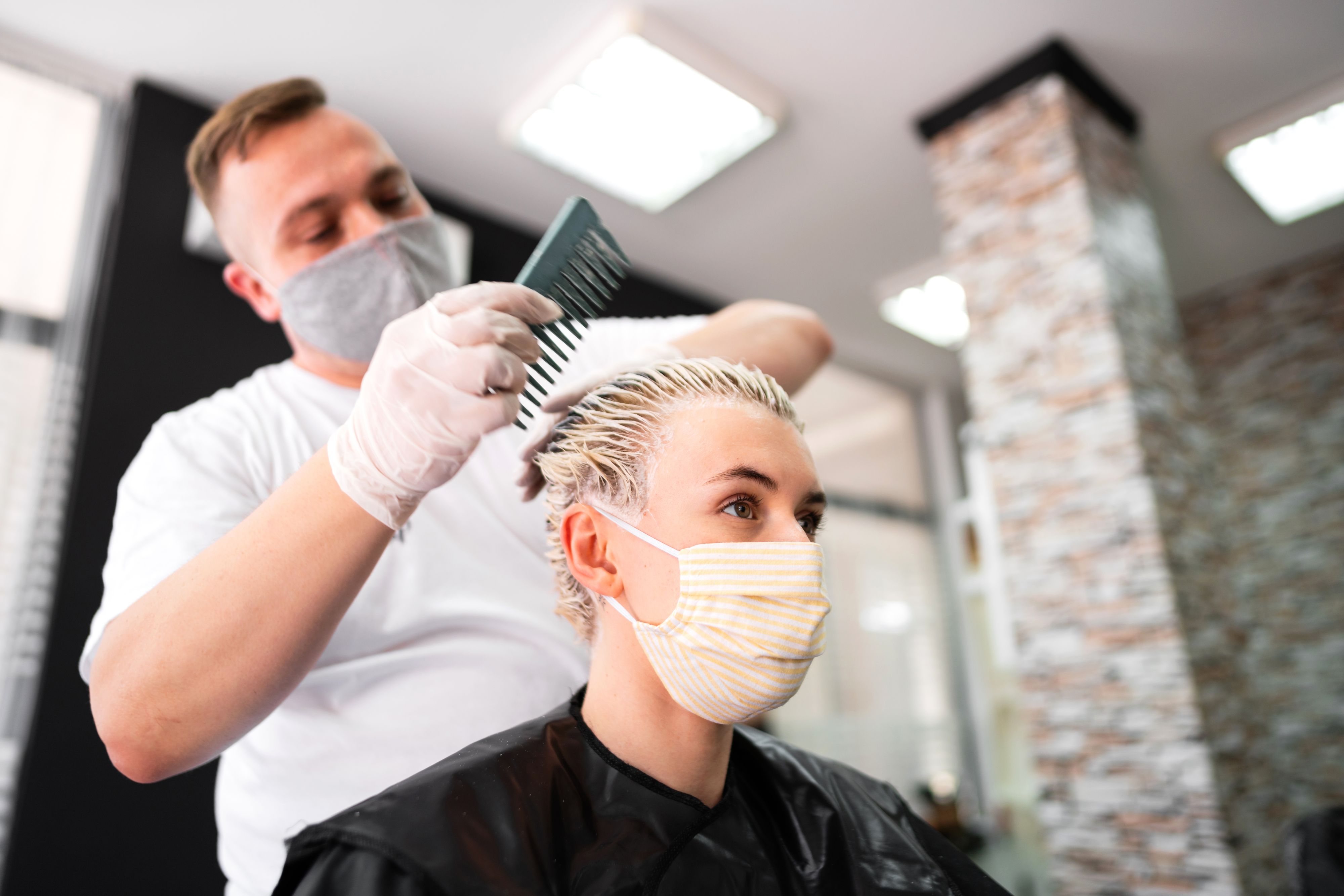 Eine junge Frau mit Schutzmaske beim Friseur. Ab 1. Juli ist diese in Österreich nicht mehr notwendig.