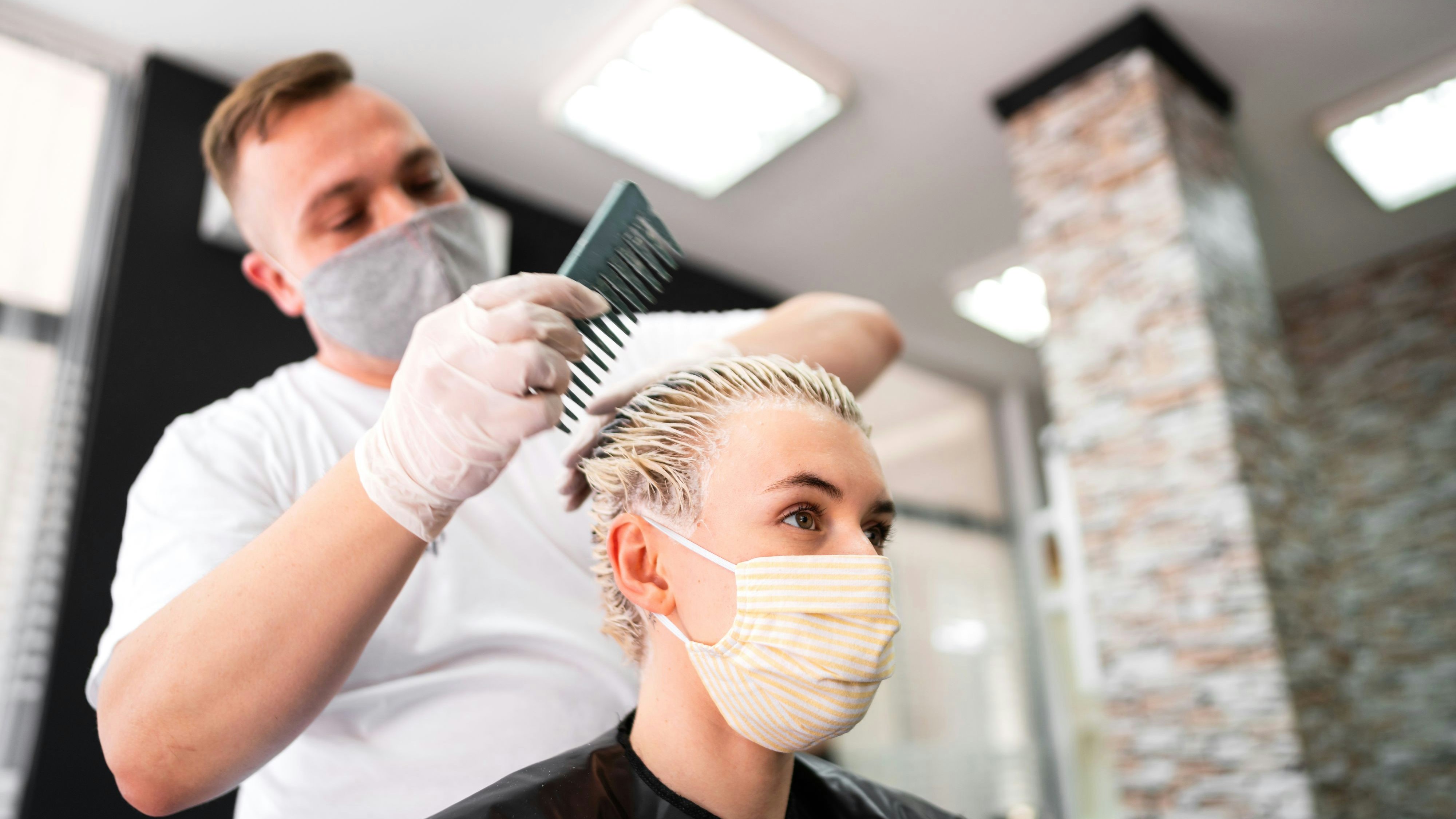 Eine junge Frau mit Schutzmaske beim Friseur. Ab 1. Juli ist diese in Österreich nicht mehr notwendig.