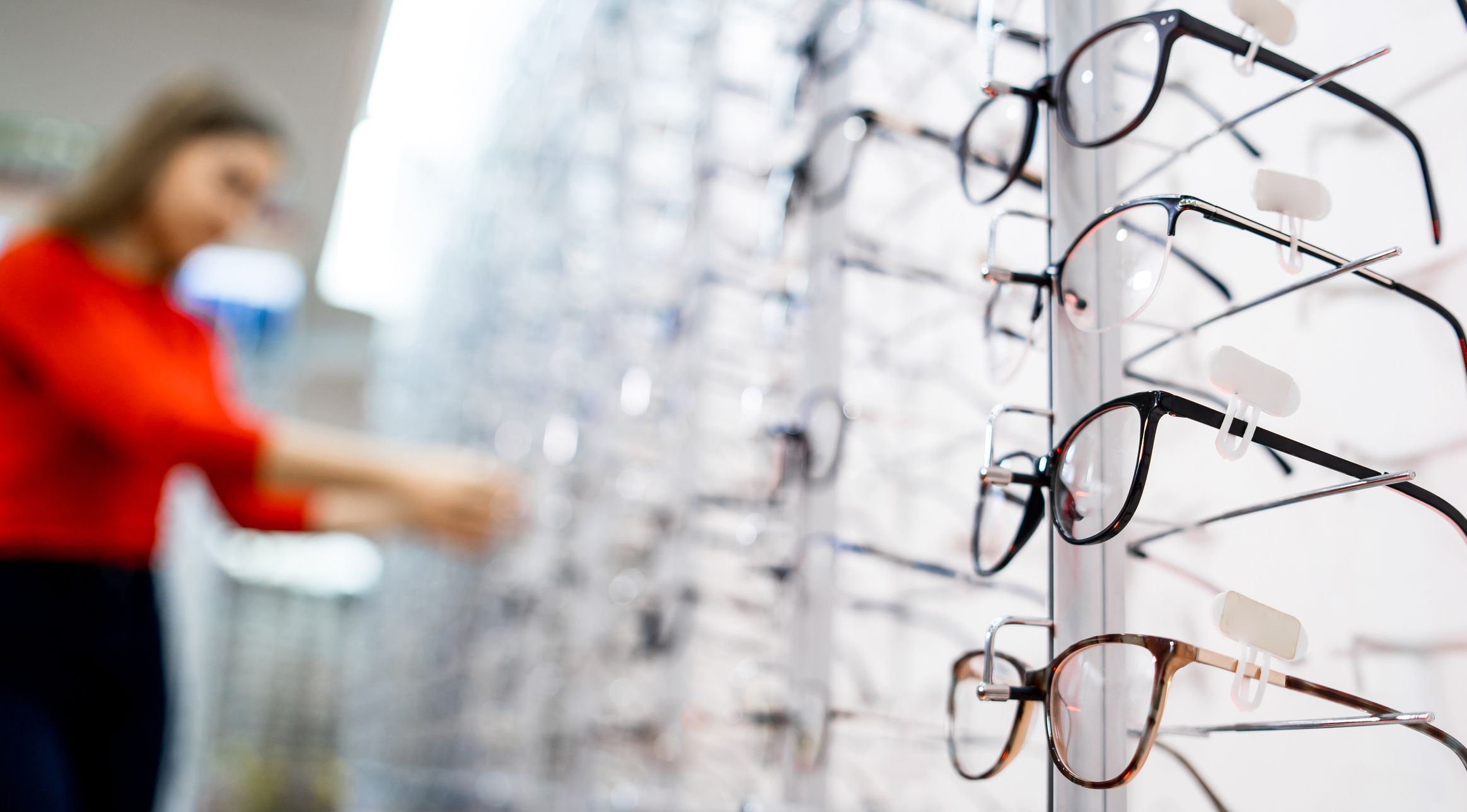 Stand with glasses in the store of optics. Beautiful girl in glasses on a background. Selective focus
