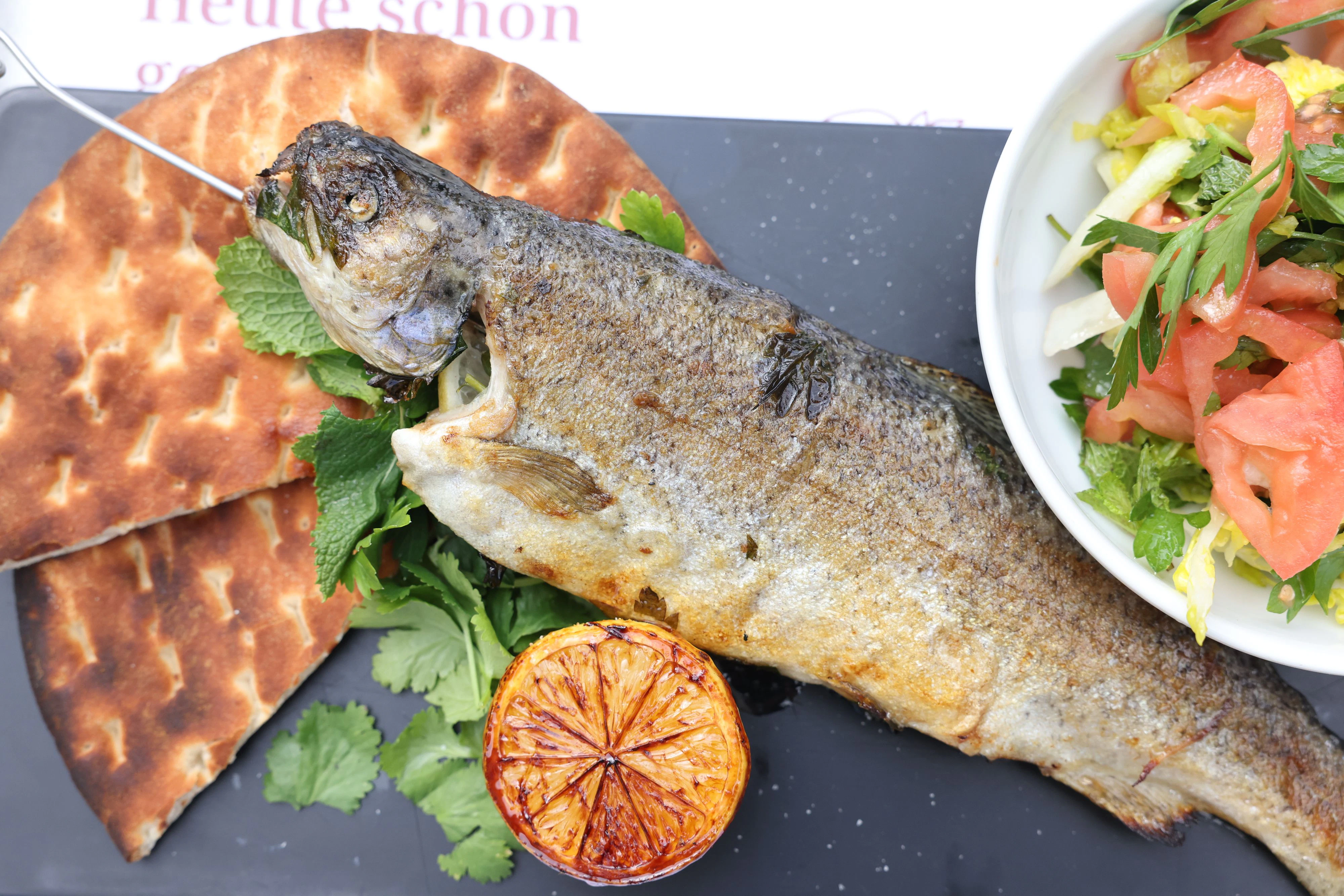 Zum Steckerlfisch (Forelle) serviert man Sommersalat, Pita und Grillzitrone.&nbsp;