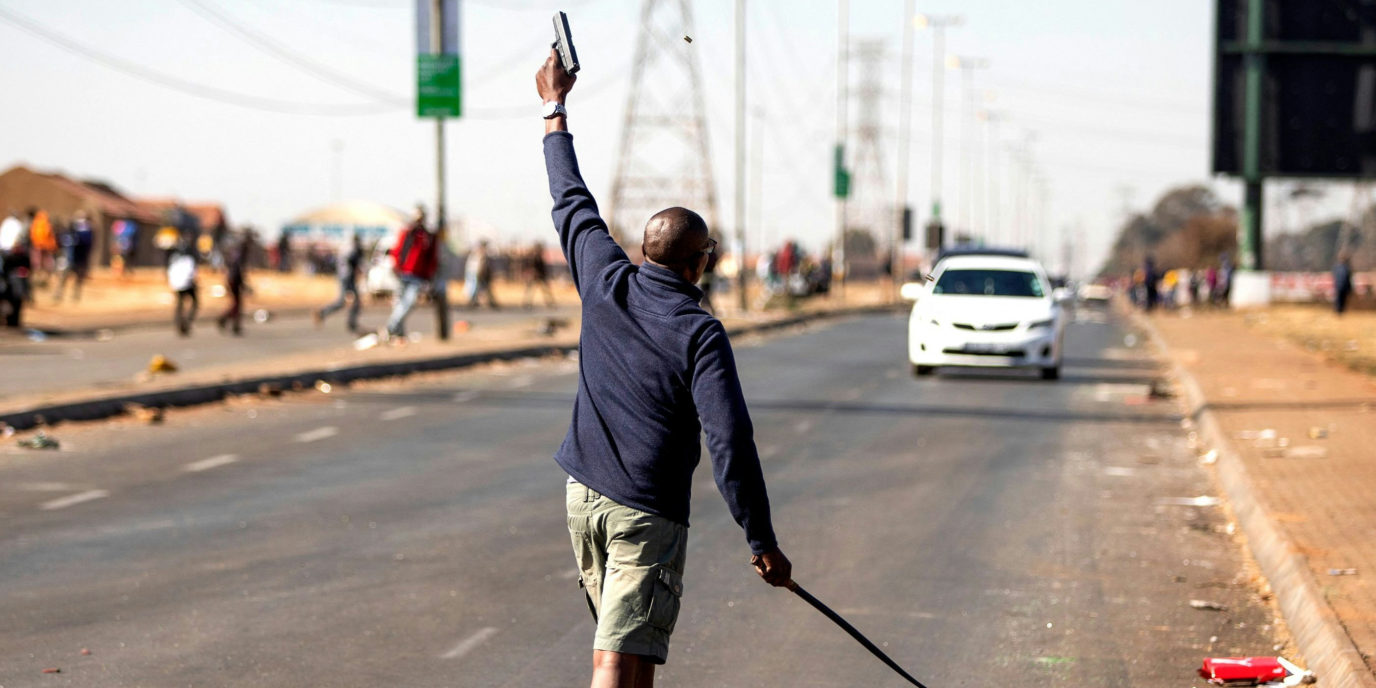 Ein Mann schießt in die Luft, um Gruppen von Plünderern auseinanderzutreiben