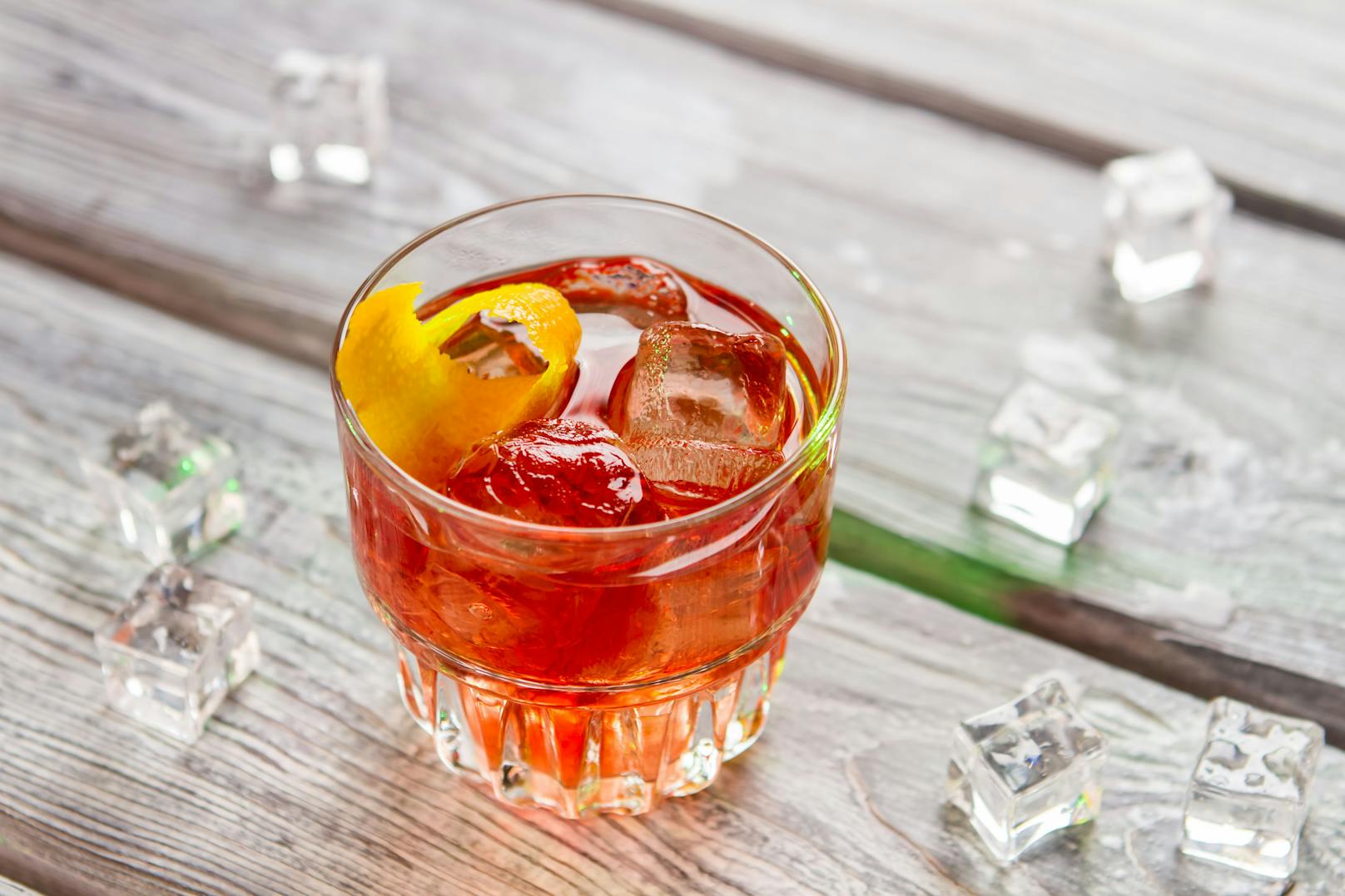 <strong>Negroni:&nbsp;</strong>Eis in ein Tumbler-Glas füllen. Roter Wermuth, Campari und Gin werden zu gleichen Teilen (je 3 cl) hinzugegeben. Und das Glas mit einem Orangenschnitz verziert.