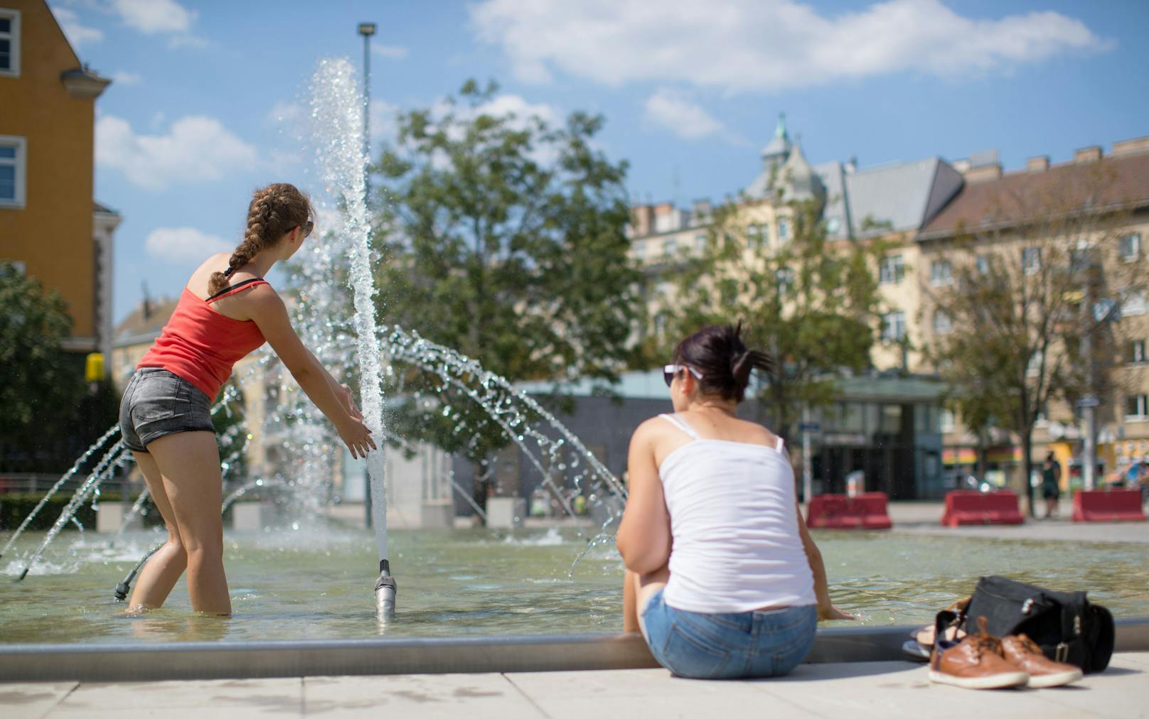 Hitzewelle in Österreich: Zwei junge Frauen erfrischen sich an einem Brunnen in Wien.