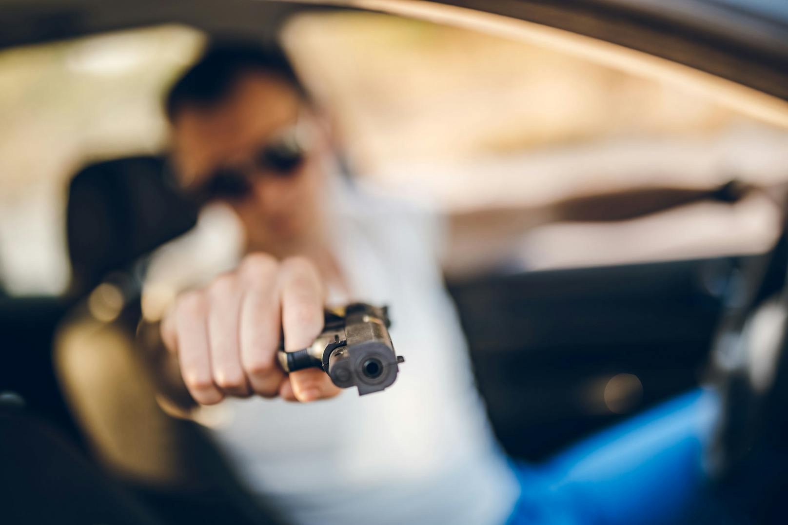 Ein junger Autofahrer richtet eine Waffe auf einen anderen Verkehrsteilnehmer. Symbolbild