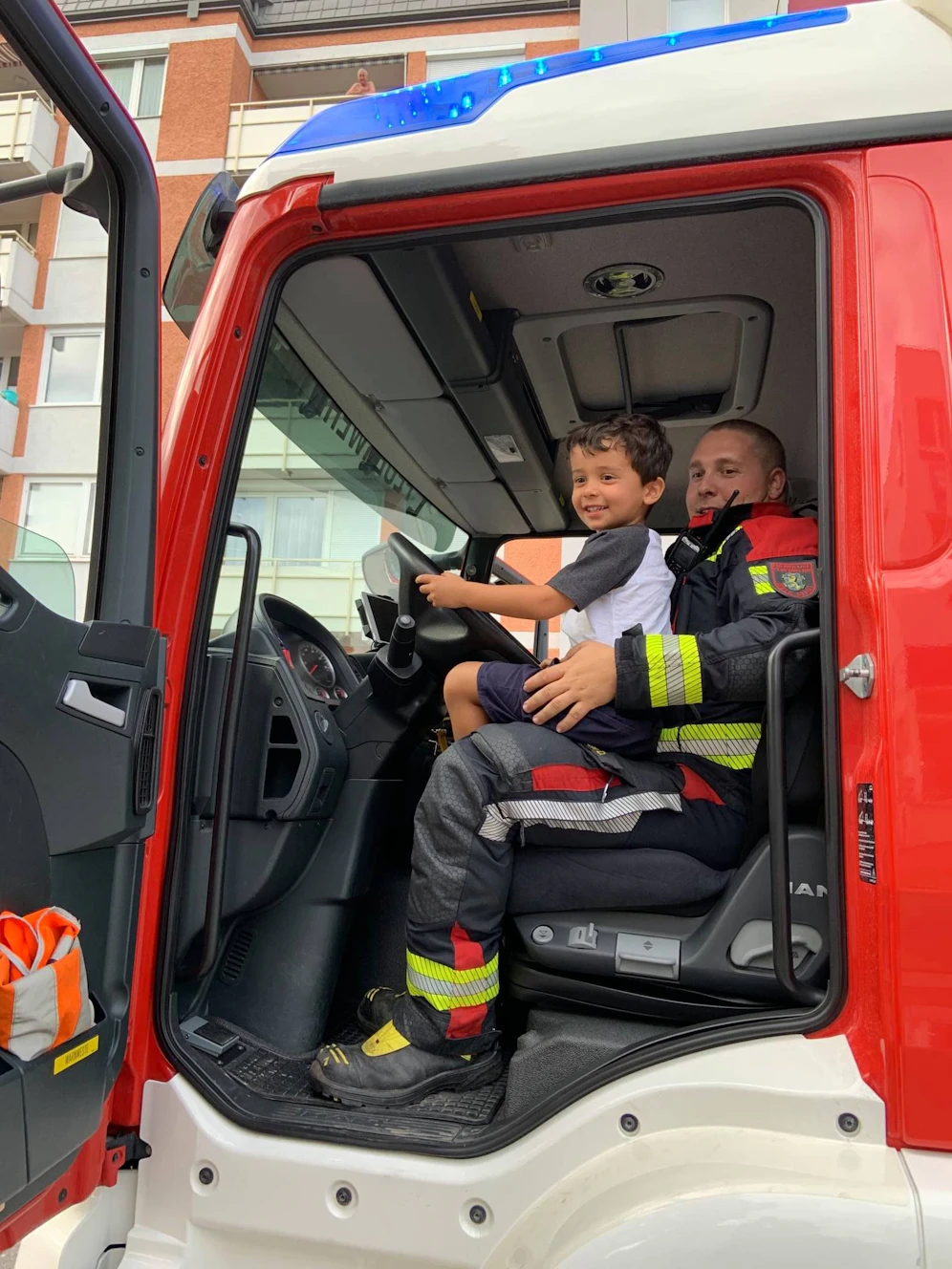 Feuerwehrmann Dominik Reiter mit dem Dreijährigen: Der Bub durfte im FF-Auto Probe sitzen.