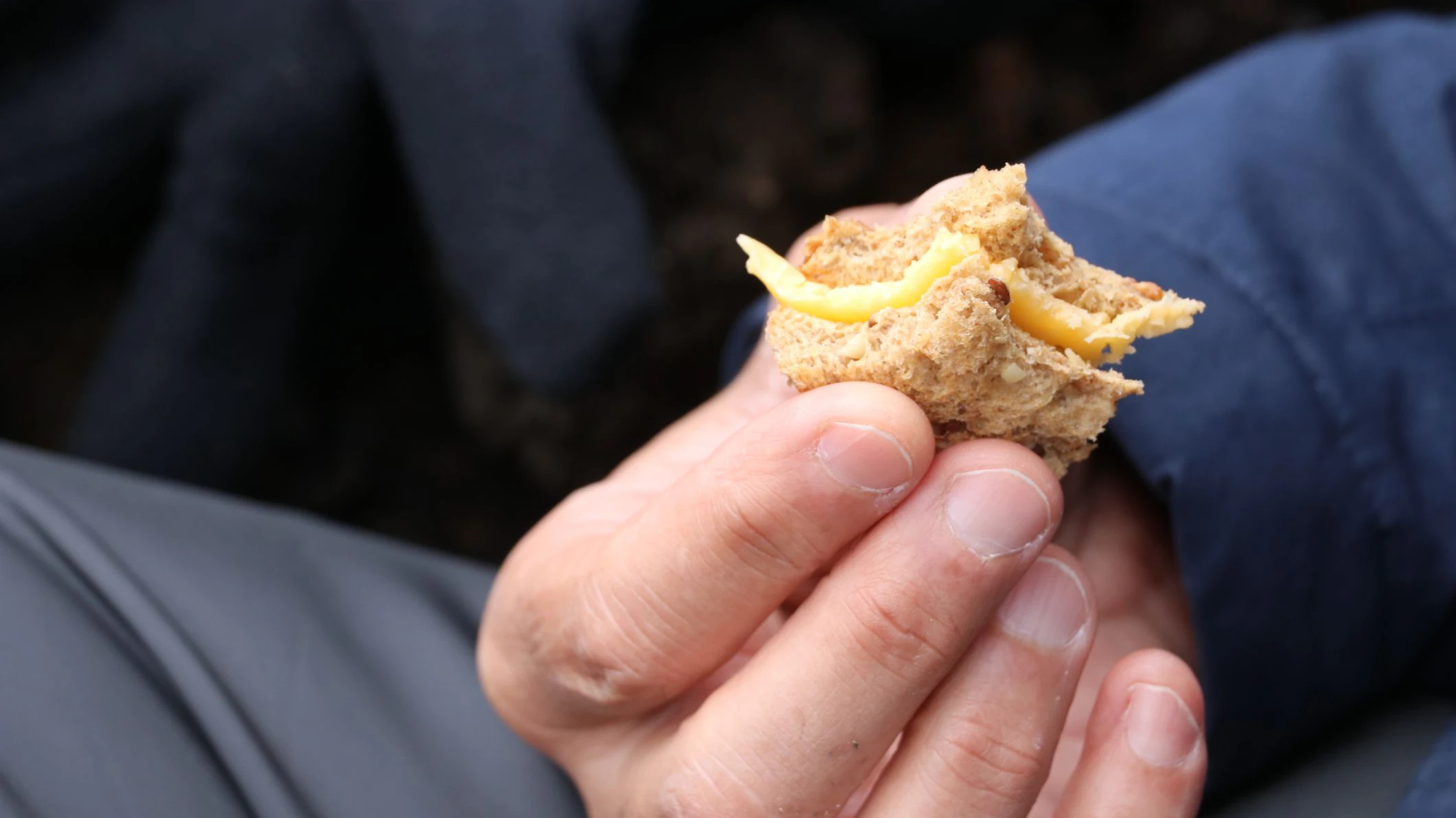 Ein Mann hält den letzten Rest eines Käsebrots in der Hand. Symbolbild
