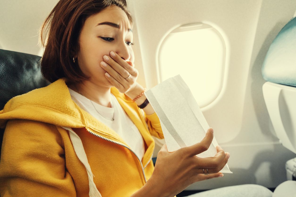 An Asian female traveler suffers from an acute attack of nausea during turbulence on a plane. The woman was seasick and airsock during air flight