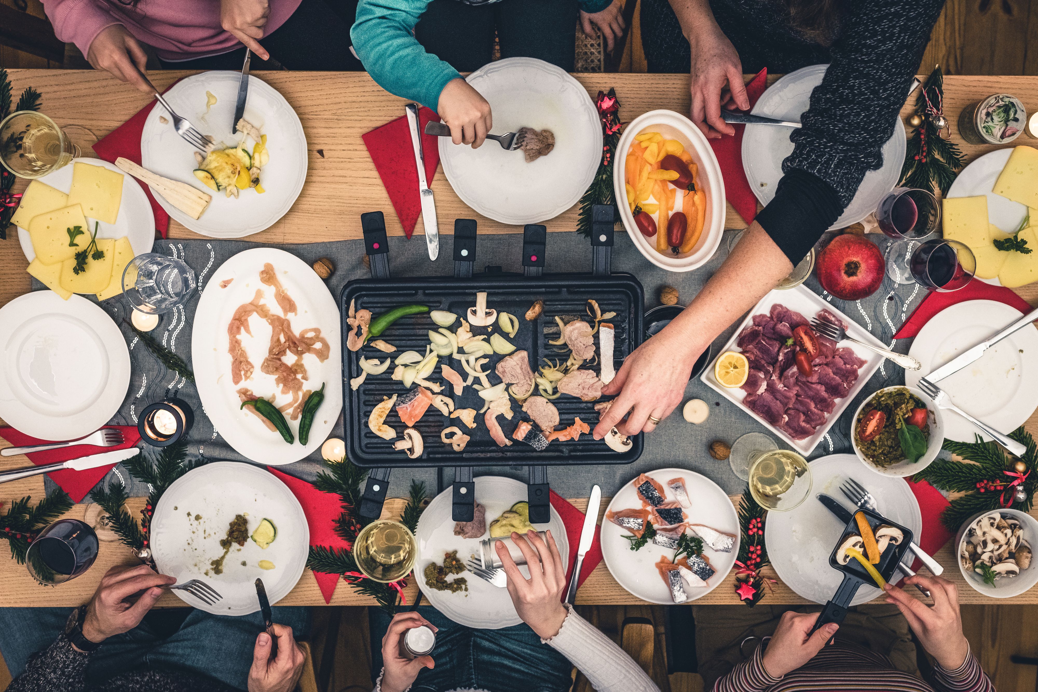 overhead view on family sitting around wooden table with raclette grill