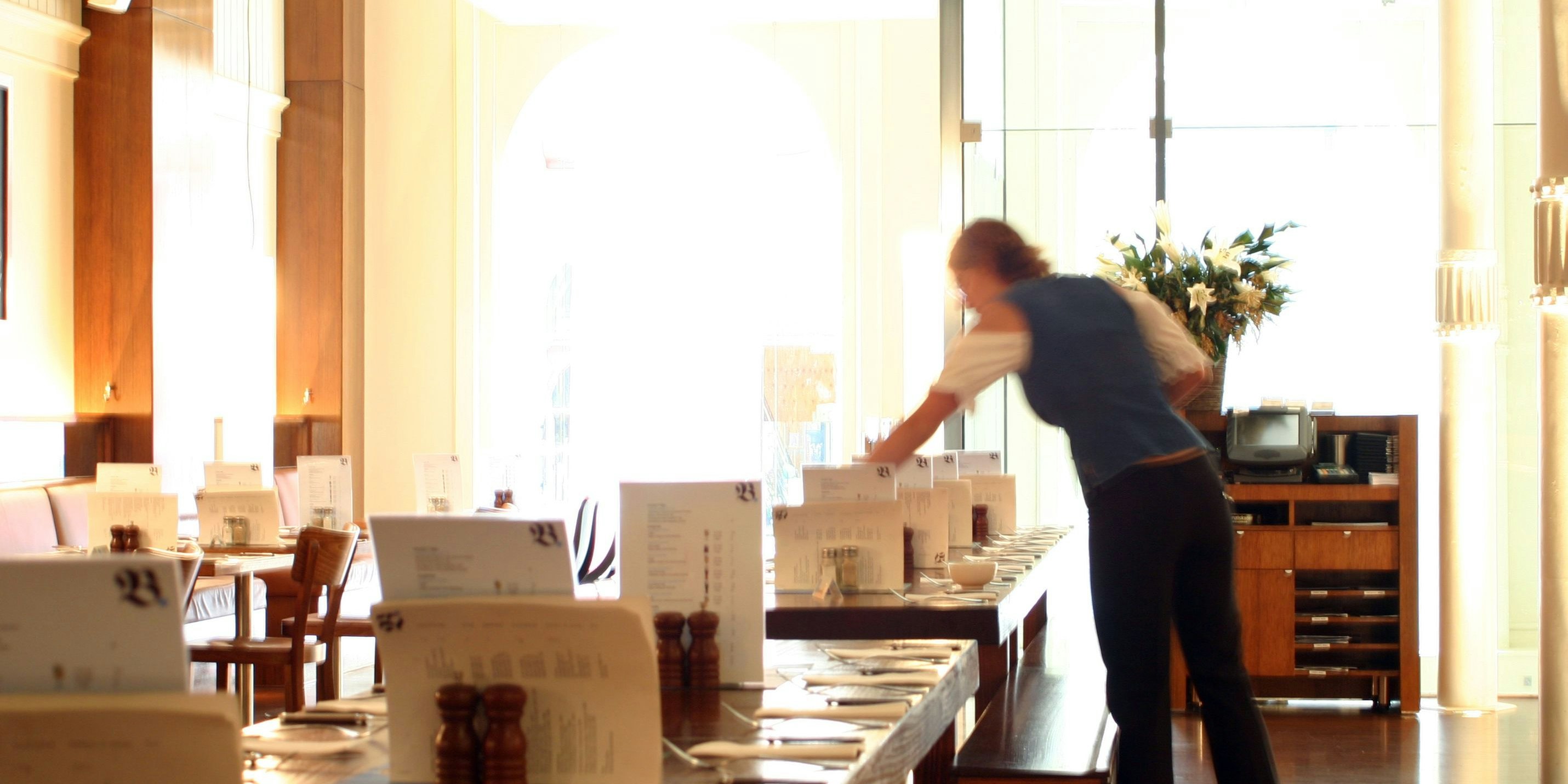 Interior German beer bar with waitress setting tables.