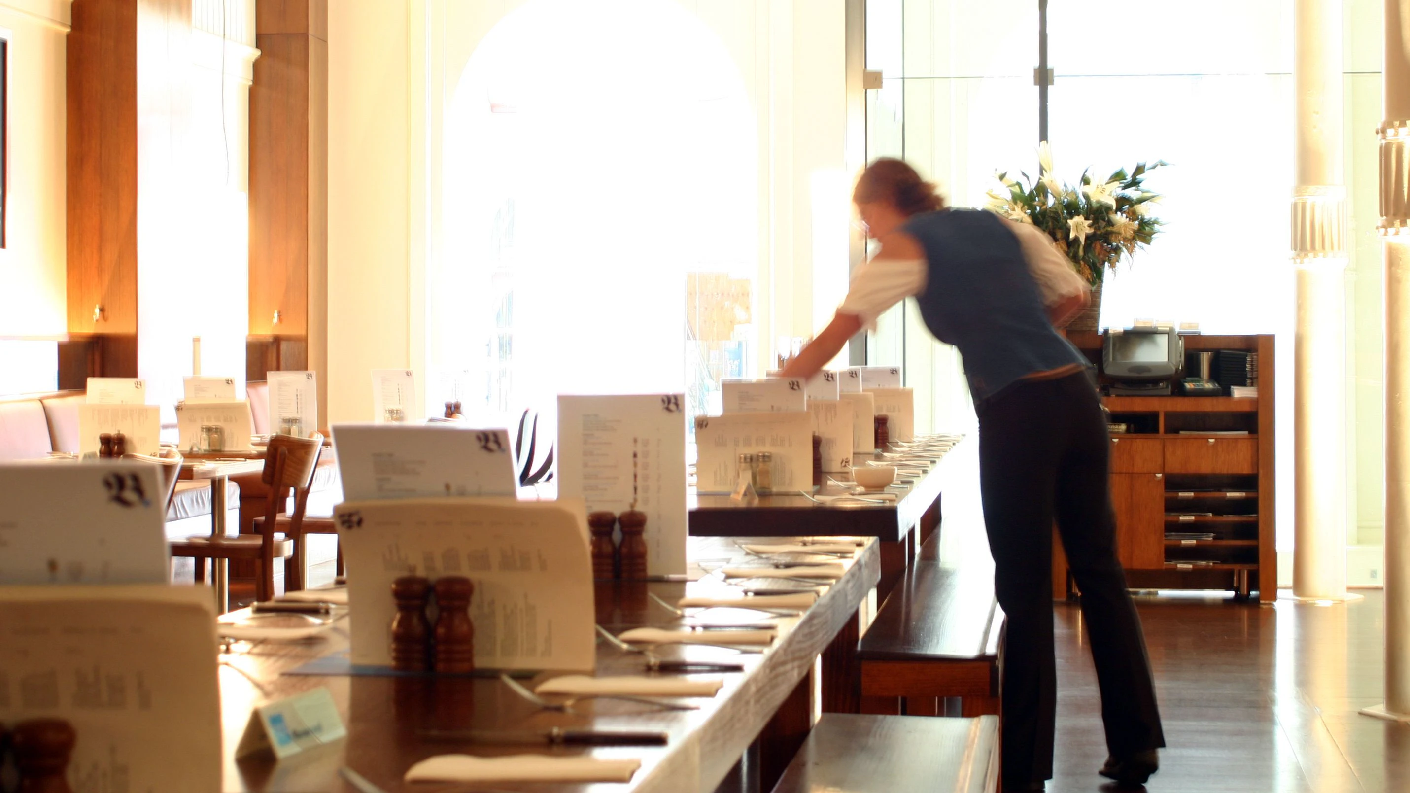 Interior German beer bar with waitress setting tables.