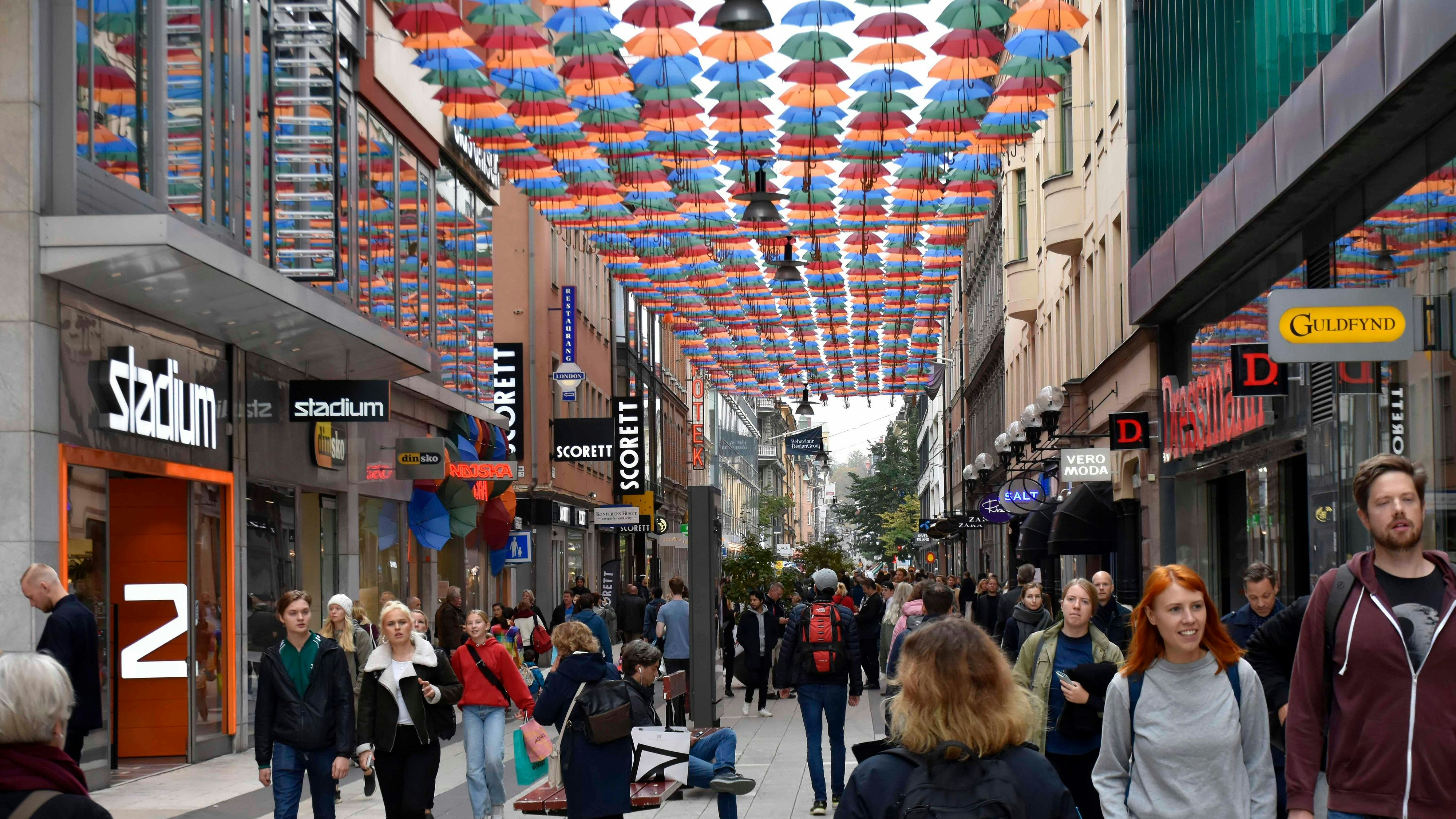 Stockholm Shopping District In Sweden Northern Europe, Building Exterior, Hanging Umbrellas, Advertisement Sign, Retail Store, People Walking Around, Standing, Looking For Items To Buy Scenery During Autumn Season