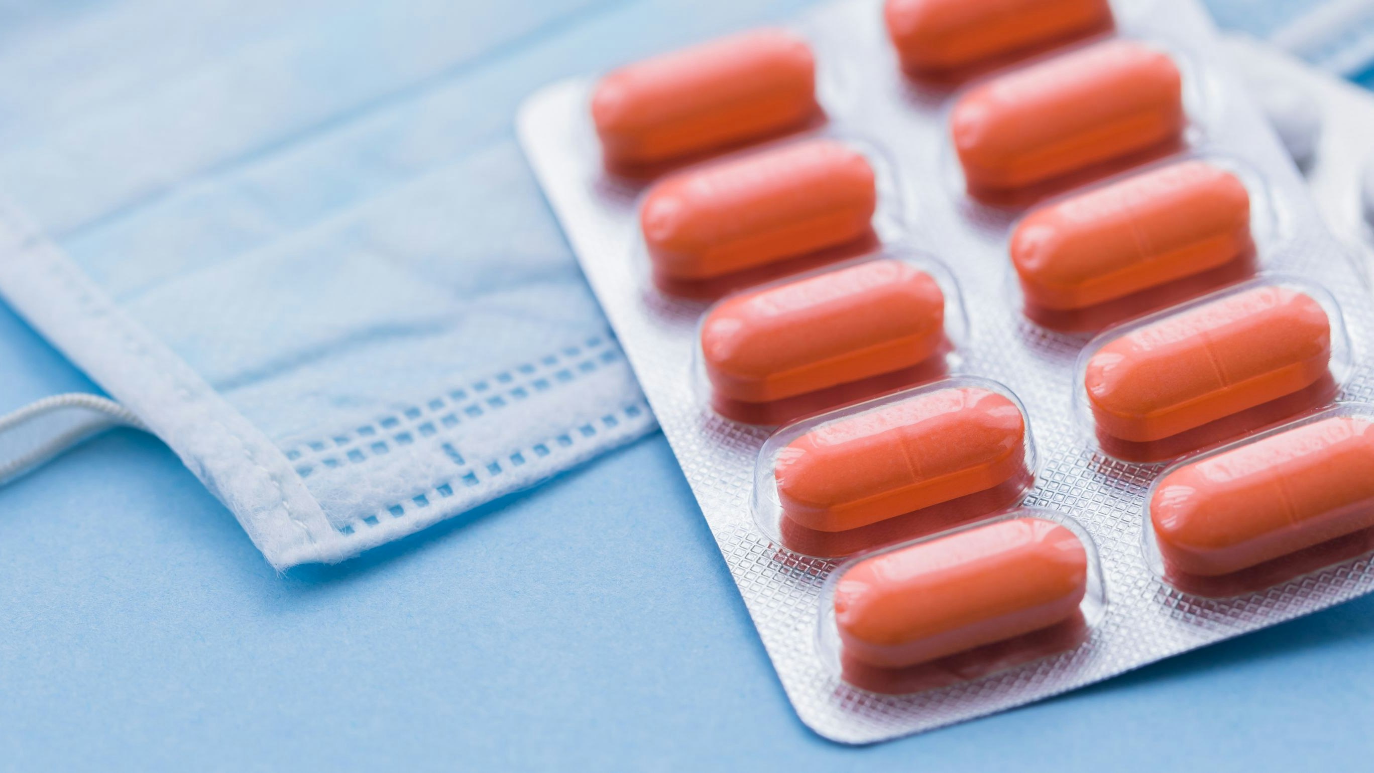 Tablets and pills on blue background with surgical protective mask, medicine drugs concept, copy space