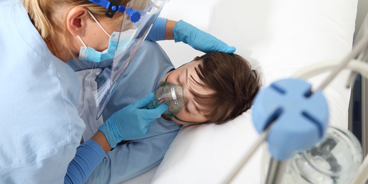 nurse takes care of the patient child in hospital bed playing with teddy bear, wearing protective masks, corona virus covid 19 protection concept,