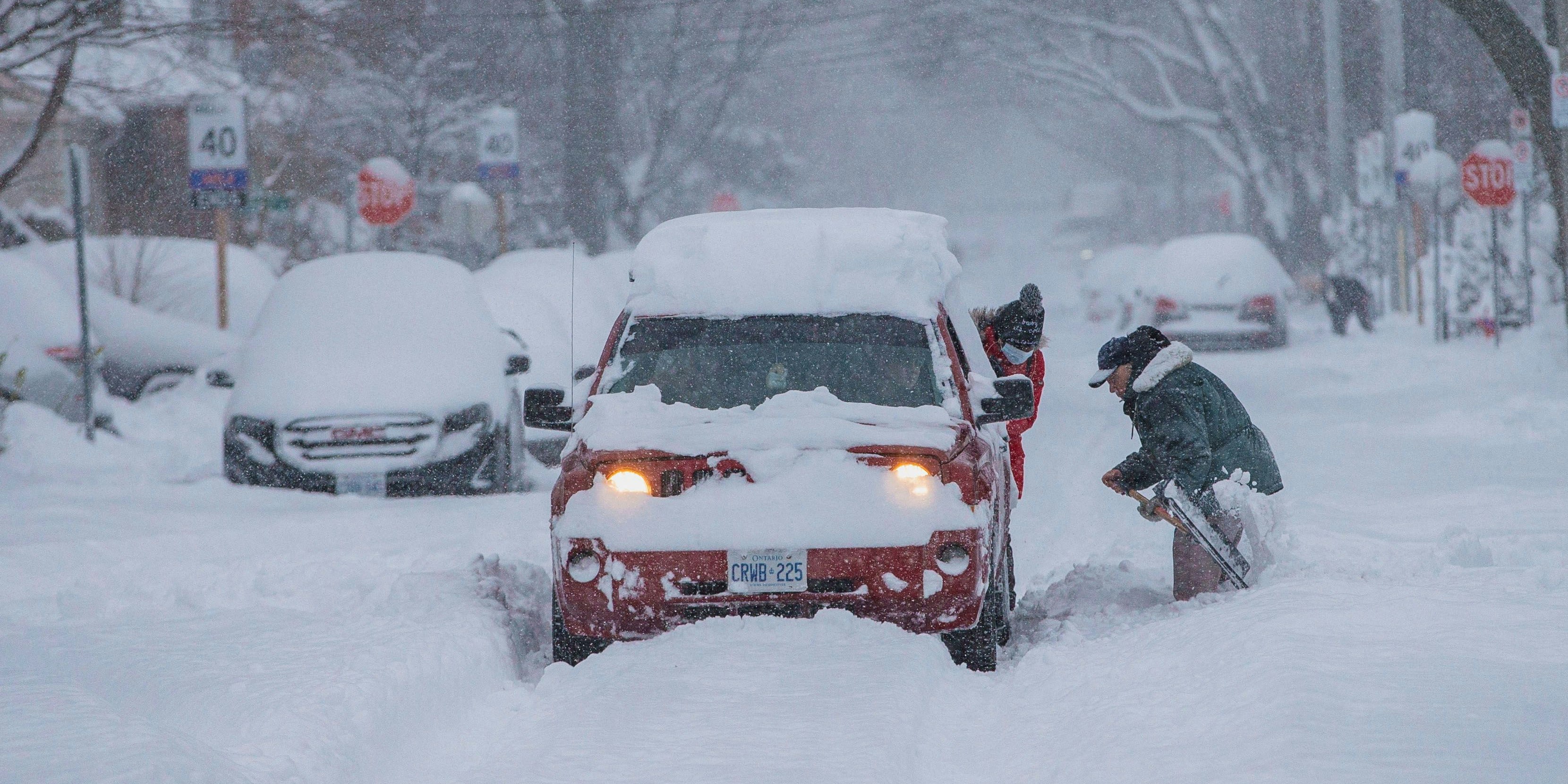 Zwei Personen versuchen in Hamilton, Ontario, ihren Wagen aus den Schneemassen zu befreien.