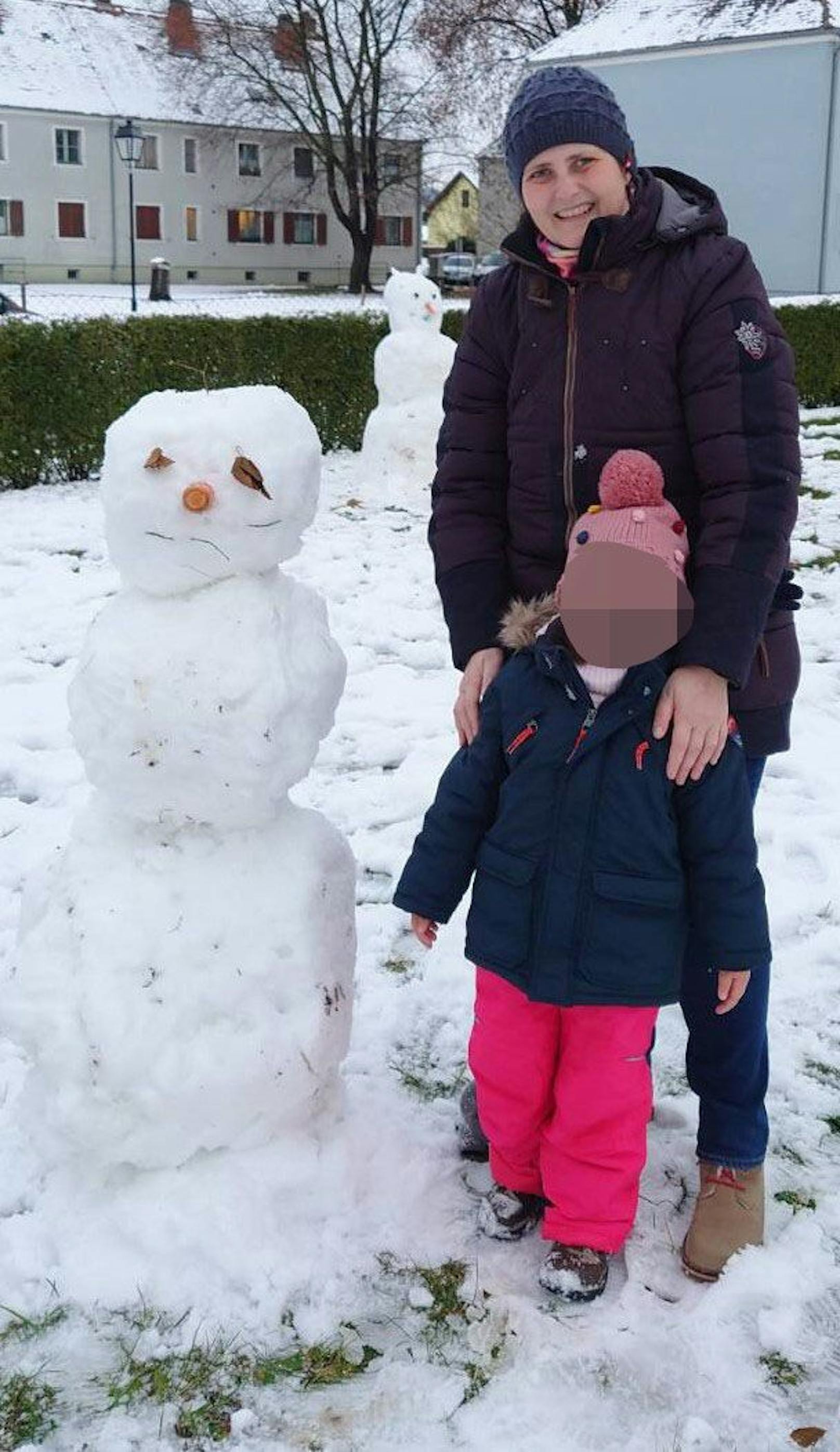 Mutter und Tochter beim Schneemann bauen.