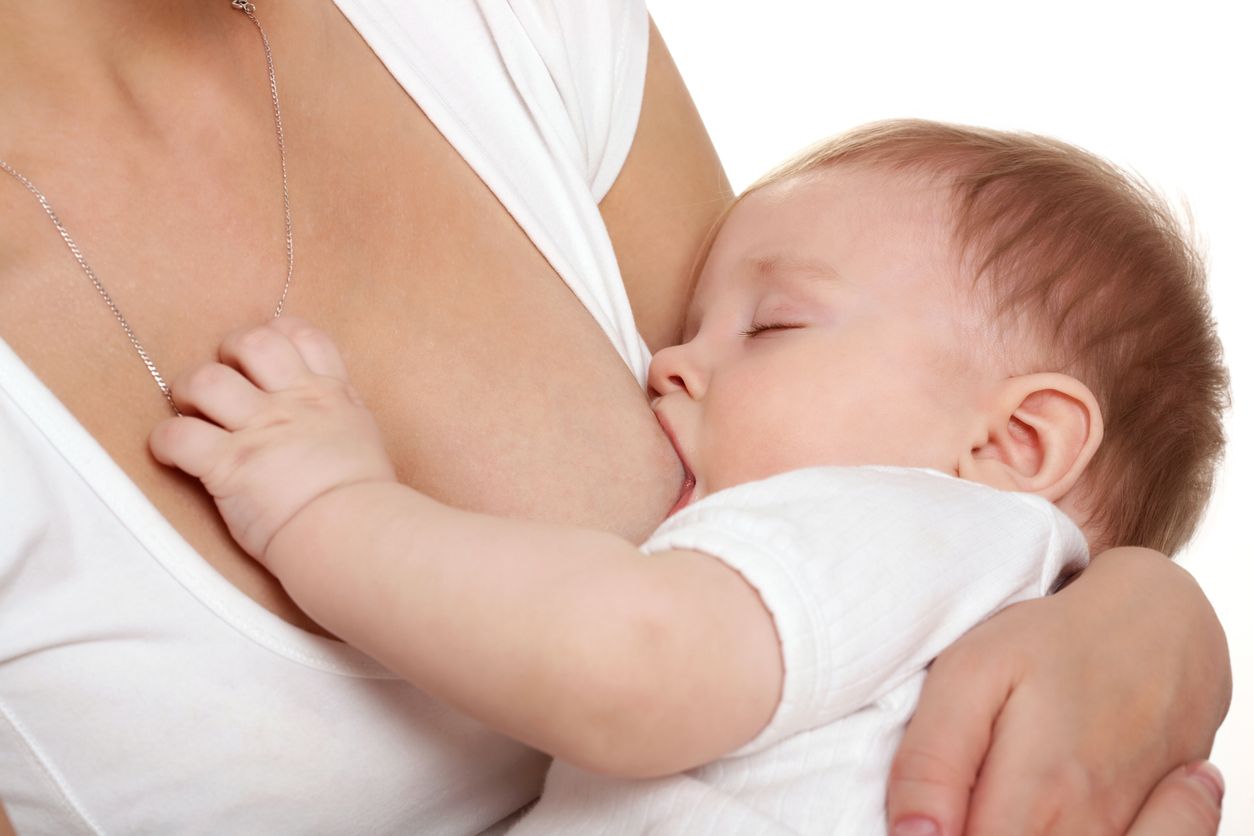Sleeping baby suckles. Studio photography, white background.