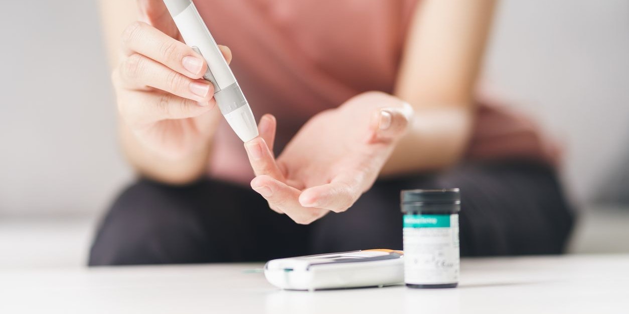 Asian woman using lancet on finger for checking blood sugar level by Glucose meter, Healthcare and Medical, diabetes, glycemia concept
