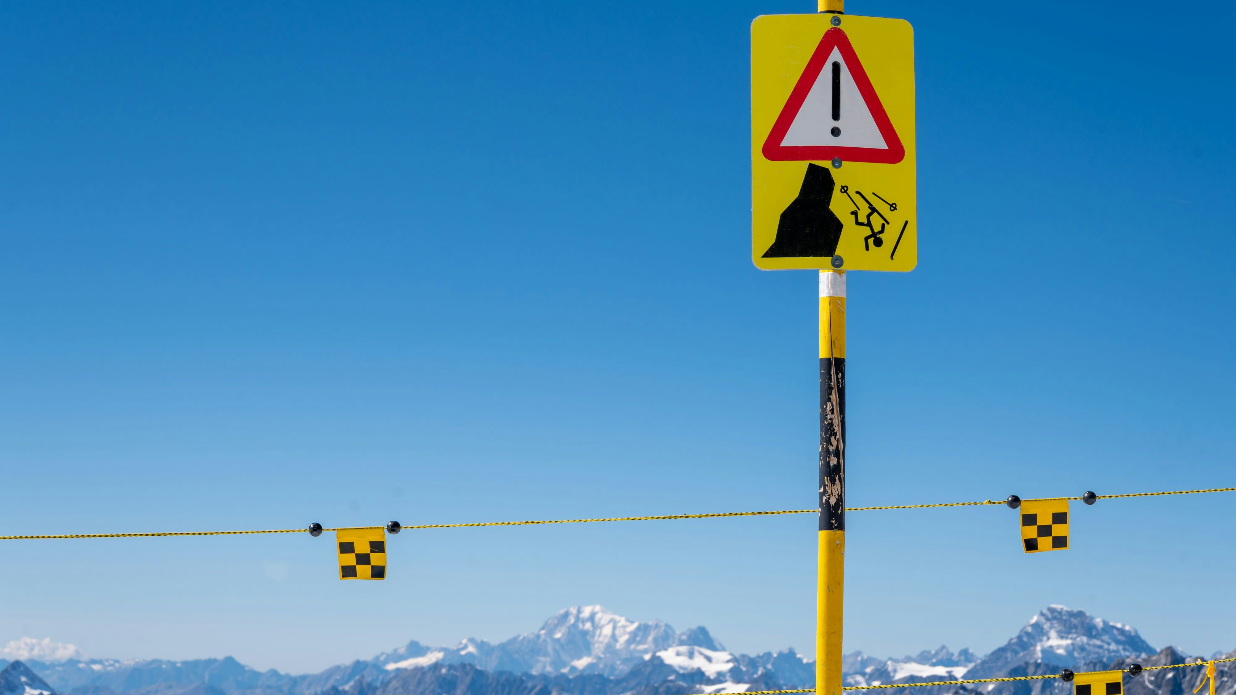 Warning sign of possible ski fall from the mountain. Yellow and black sign.