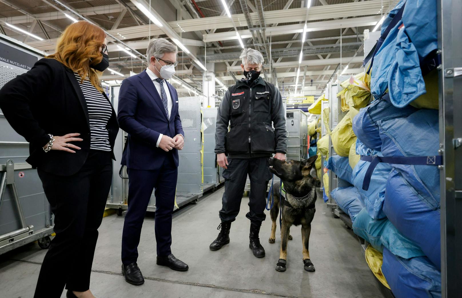 Heike Fetka-Blüthner (Vorstand Zollamt Österreich) und Finanzminister Magnus Brunner mit einem Diensthundeführer und Zoll-Diensthund Django im Post-Logistikzentrum Wien-Inzersdorf.