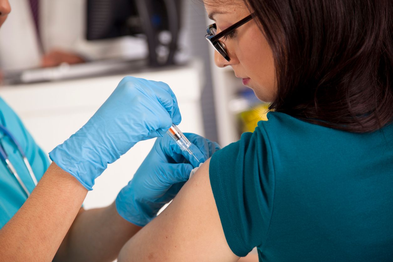 Flu season!  Nurse at pharmacy or clinic giving flu shot to a female patient.  Syringe, needle.