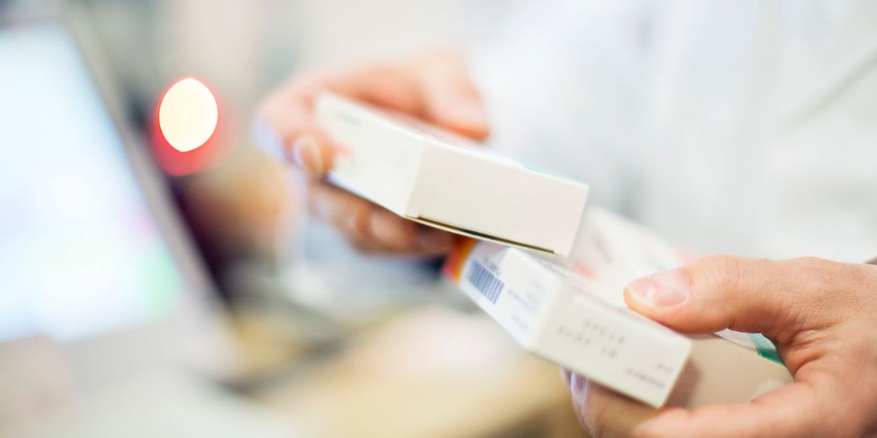 Cropped image of pharmacist holding medicines. Male chemist is at pharmacy. Focus is on pill box.