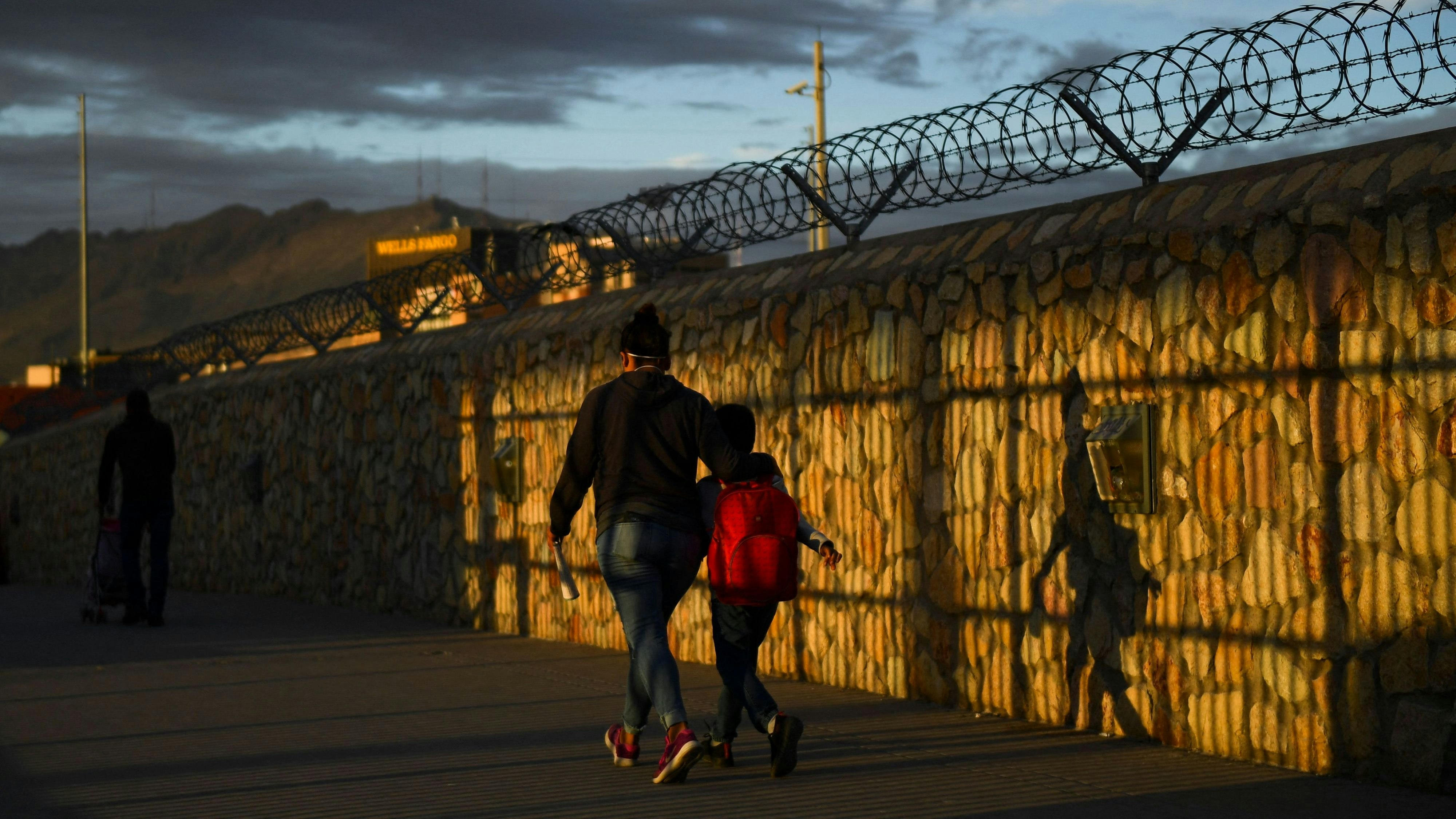 Download von www.picturedesk.com am 27.01.2022 (07:29).  TOPSHOT - People walk along a fence after crossing the border from Mexico at the US Customs and Border Protection Paso del Norte Port of Entry along the US-Mexico border between Texas and Chihuahua state on December 9, 2021 in El Paso, Texas. (Photo by Patrick T. FALLON / AFP) - 20211209_PD16098 - Rechteinfo: Rights Managed (RM) Nur für redaktionelle Nutzung! Werbliche Nutzung erfordert Freigabe: bitte schicken Sie uns eine Anfrage.