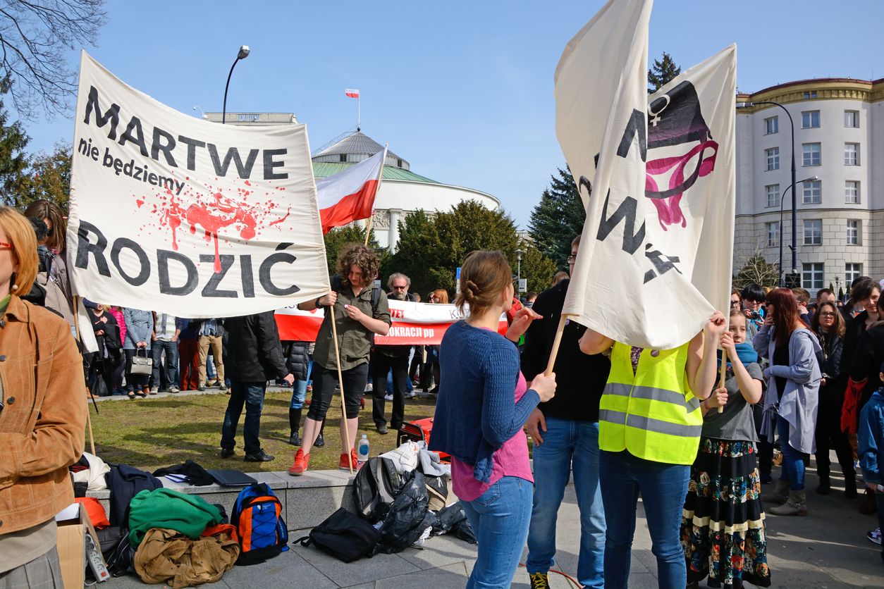 Warsaw, Poland - April 3rd, 2016: People preparing protest against stricter anti-abortion law, in front of the Polish parliament. People developing banners with women rights slogans. Protest organized by party Razem (Together). Horizontal image in a sunny day.