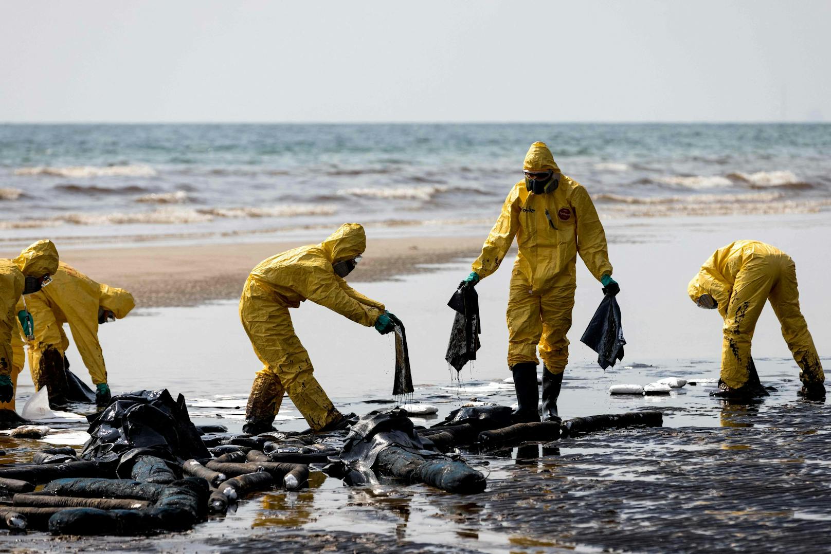 Mit voller Schutzmontur versuchen die Helfer, den Strand von dem Öl zu reinigen.
