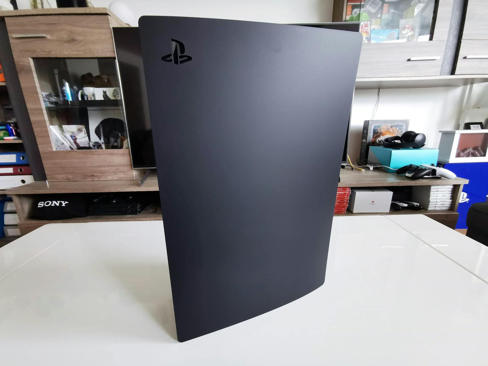 ...das PS5-Cover an der Stelle des eingestanzten PlayStation-Logos an und zieht mit der anderen Hand etwas kräftiger das Cover von der Konsole ab.