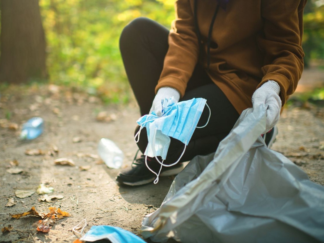 Teenage girl cleaning up garbage outdoors during COVID-19 pandemic