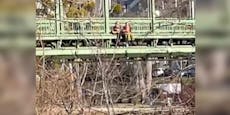 Paar klettert über Donaukanal-Geländer, genießt Sonne