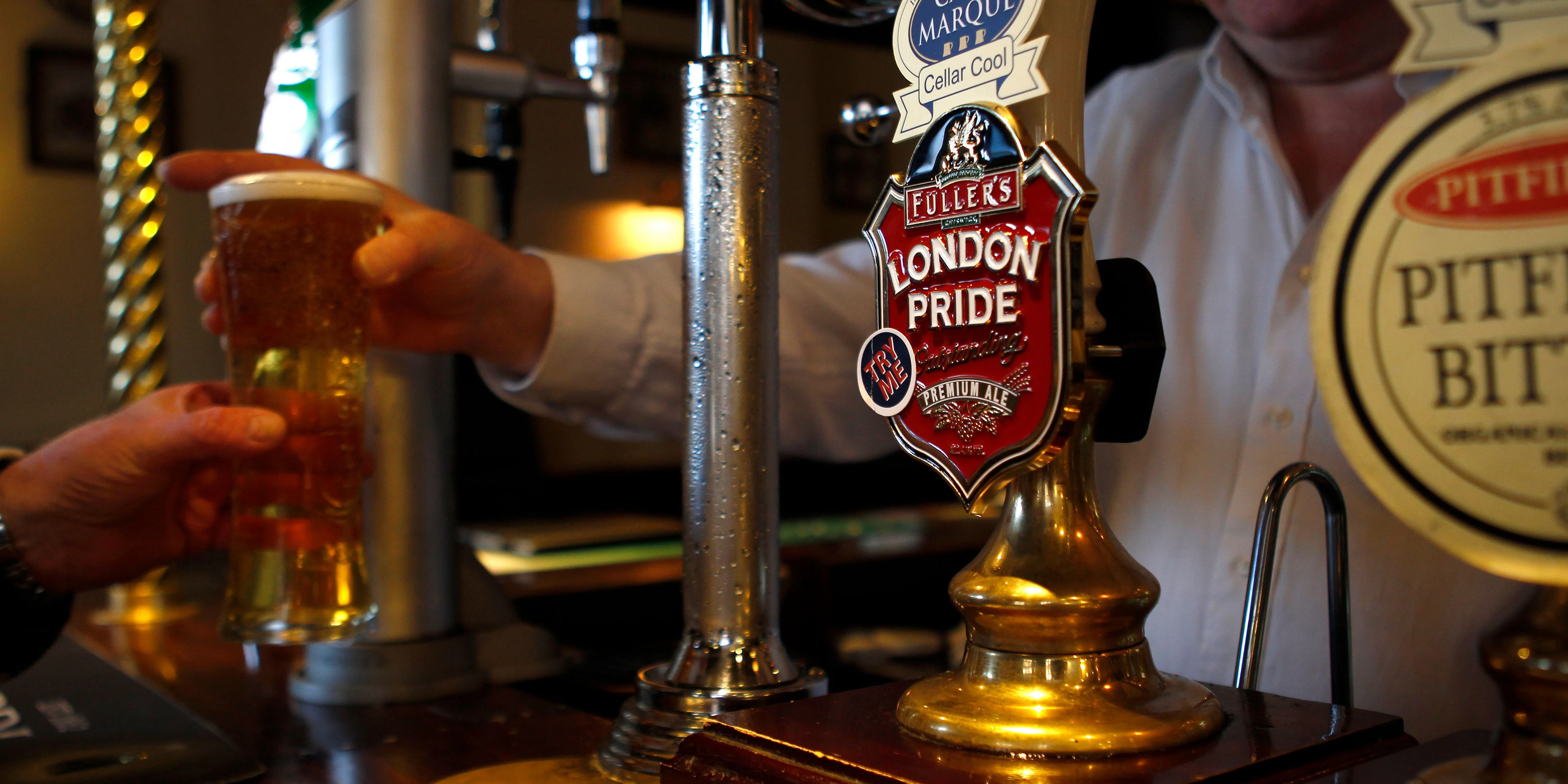 A barman passes a drink to a customer at The Bow Bells pub in east London January 26, 2012.  The pub is within a mile of the Olympic Park where the 2012 Olympic Games will take place.   REUTERS/Eddie Keogh (BRITAIN)