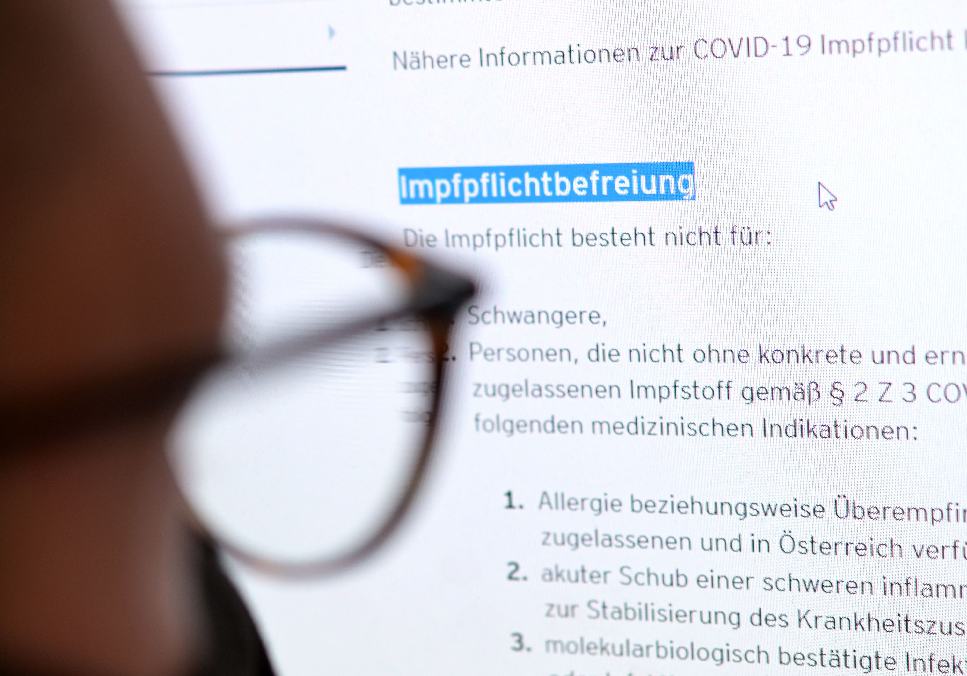 Ein junger Mann liest auf der Website eines Bundeslandes über Regelungen zur Befreiung von der Covid-19 Impfpflicht.
