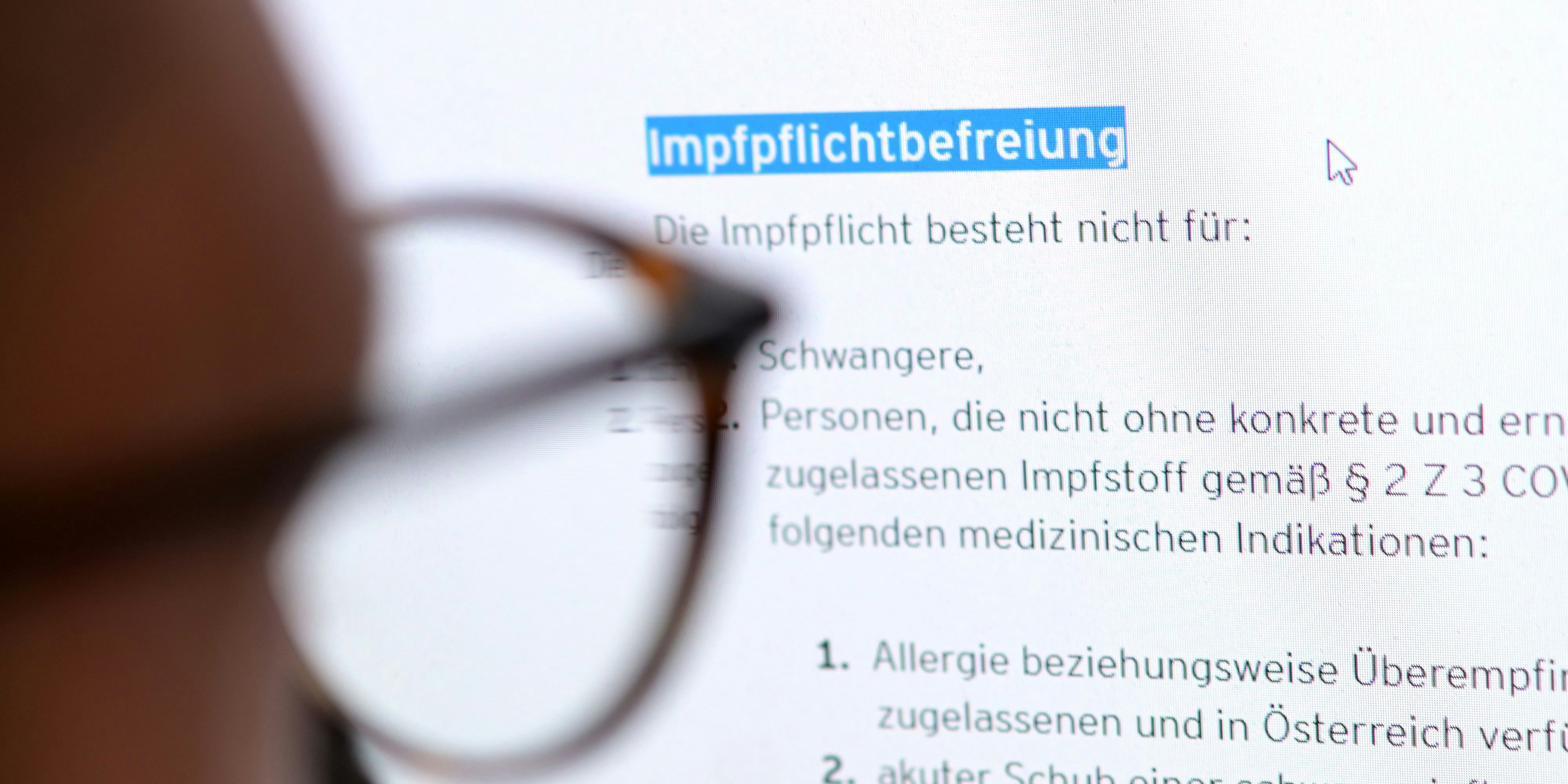 Ein junger Mann liest auf der Website eines Bundeslandes über Regelungen zur Befreiung von der Covid-19 Impfpflicht 