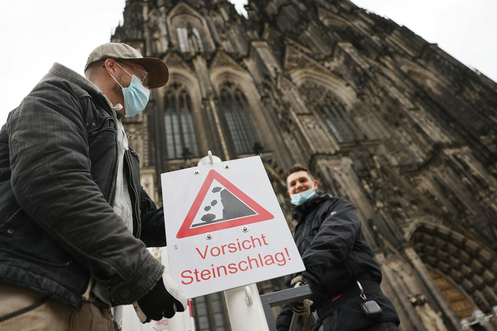 Vor dem Kölner Dom warnen Schilder vor der Gefahr von möglichem Steinschlag.