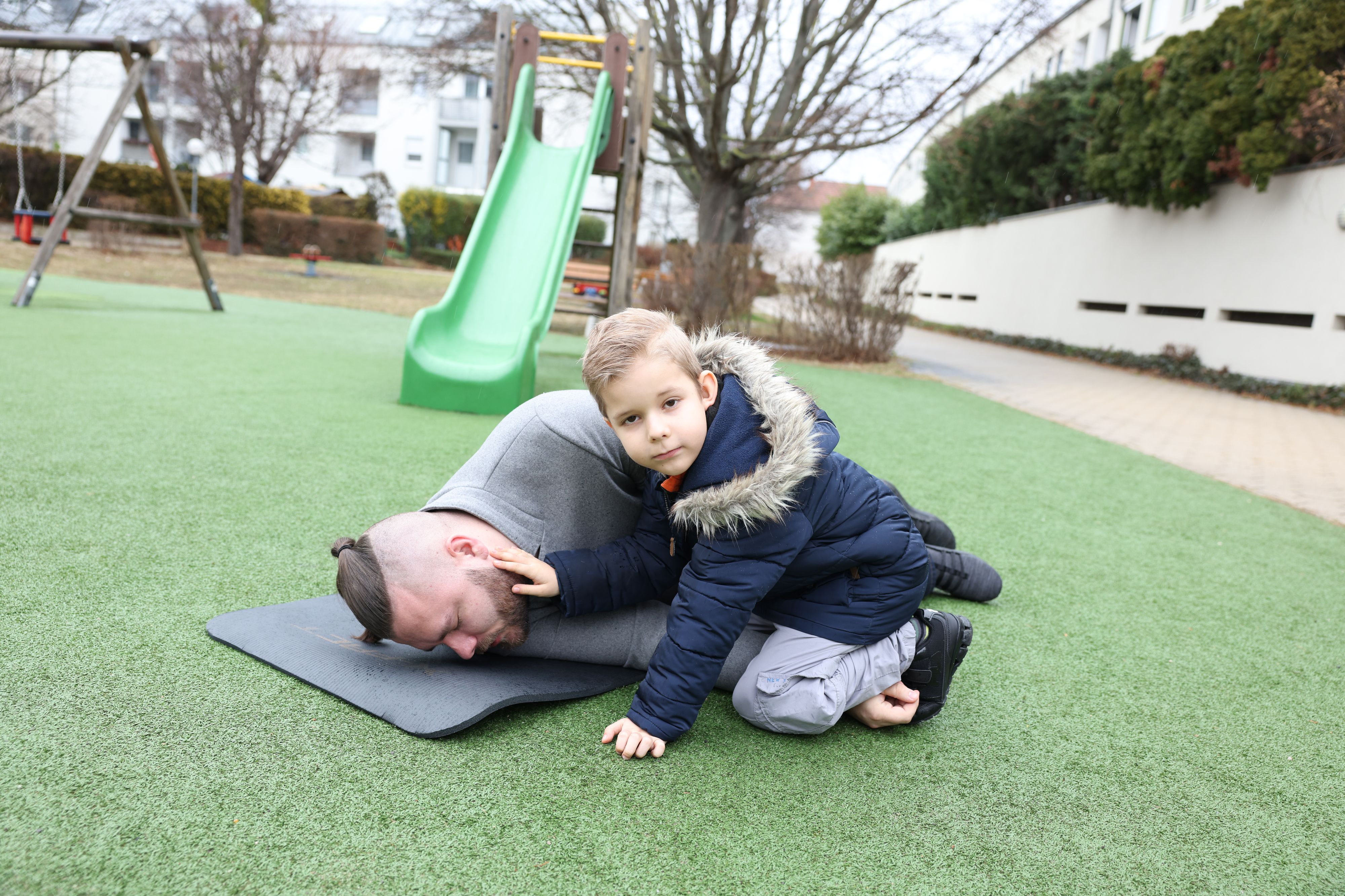 Elias (6) rettete seiner Mama das Leben. An seinem Papa Jan – er ist selbst Notfallsanitäter bei der Wiener Berufsrettung – zeigt der kleine Held vor, wie er es gemacht hat.