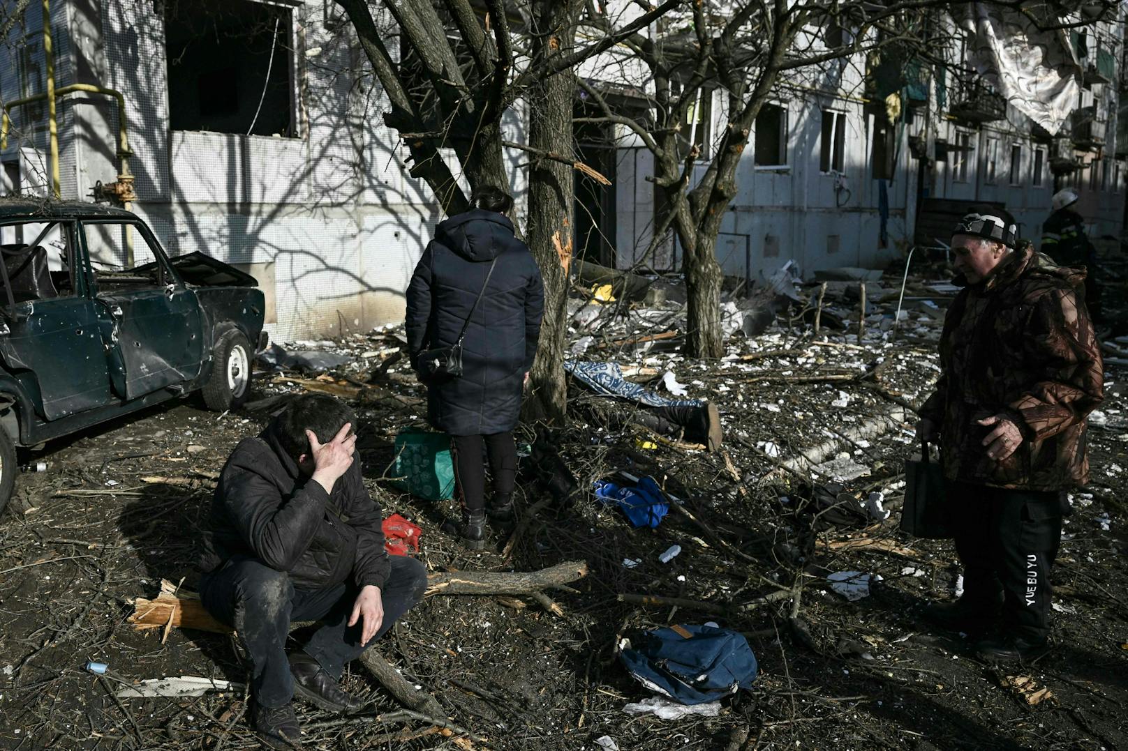 Zivilisten neben der Leiche eines Angehörigen an der Einschlagstelle einer russischen Rakete in&nbsp;Tschuhujiw am 24. Februar 2022.