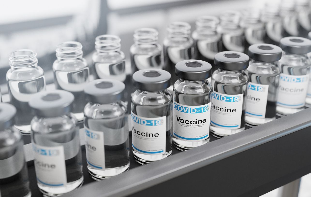 Coronavirus Vaccine vials in a row, being bottled on a production line in a lab. Labeled with COVID-19 vaccine on blue color.