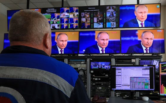 EIn Mann beobachtet eine Live-Übertragung von Russlands Präsident Wladimir Putin (Archivbild).