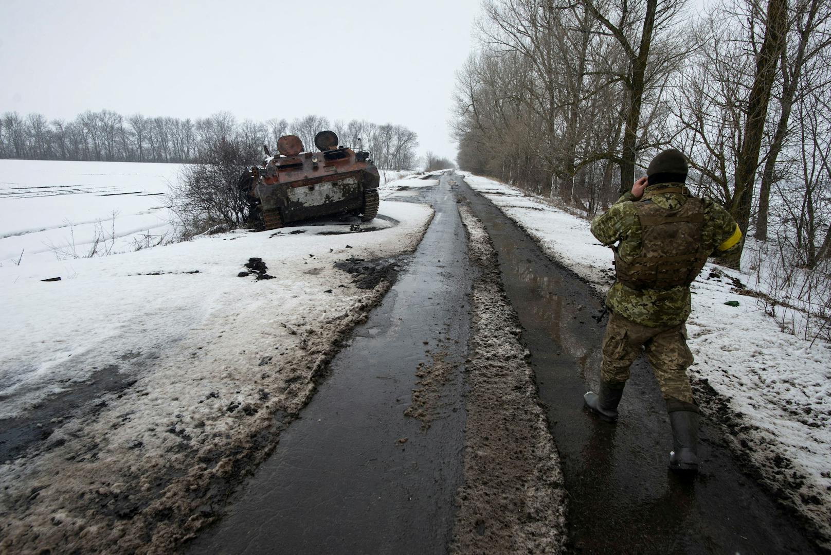 Ein ukrainischer Soldat neben einem ausgebrannten russischen Panzerfahrzeug.