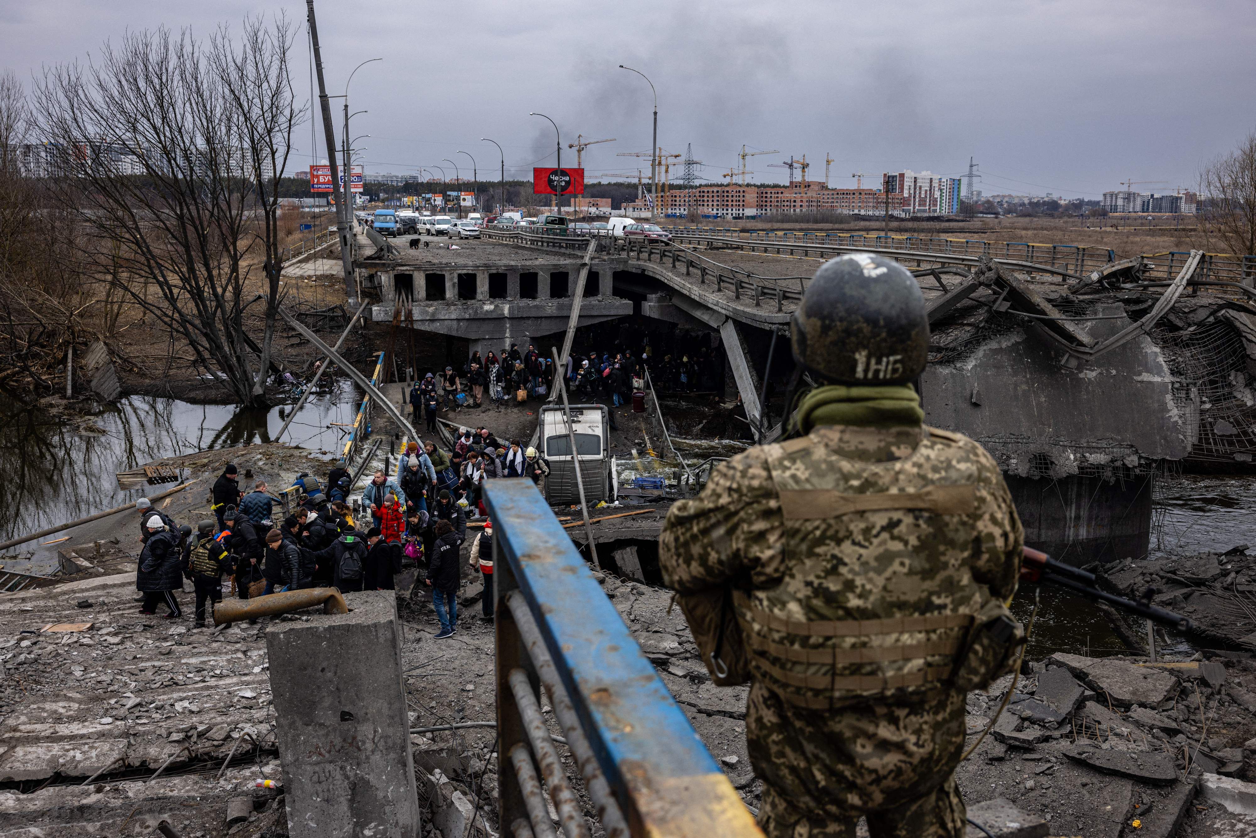 Flüchtende Ukrainerinnen und Ukrainer beim Überqueren einer zerstörten Brücke in der nordwestlich von Kiew gelegenen Stadt Irpin.