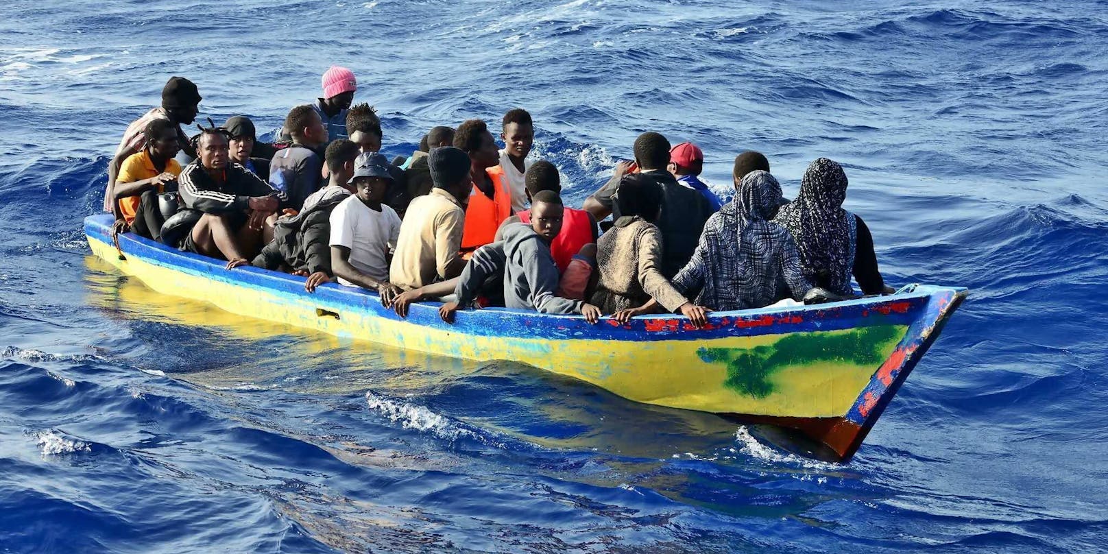 Ein völlig überfülltes Boot mit afrikanischen Flüchtlingen mitten im Mittelmeer.